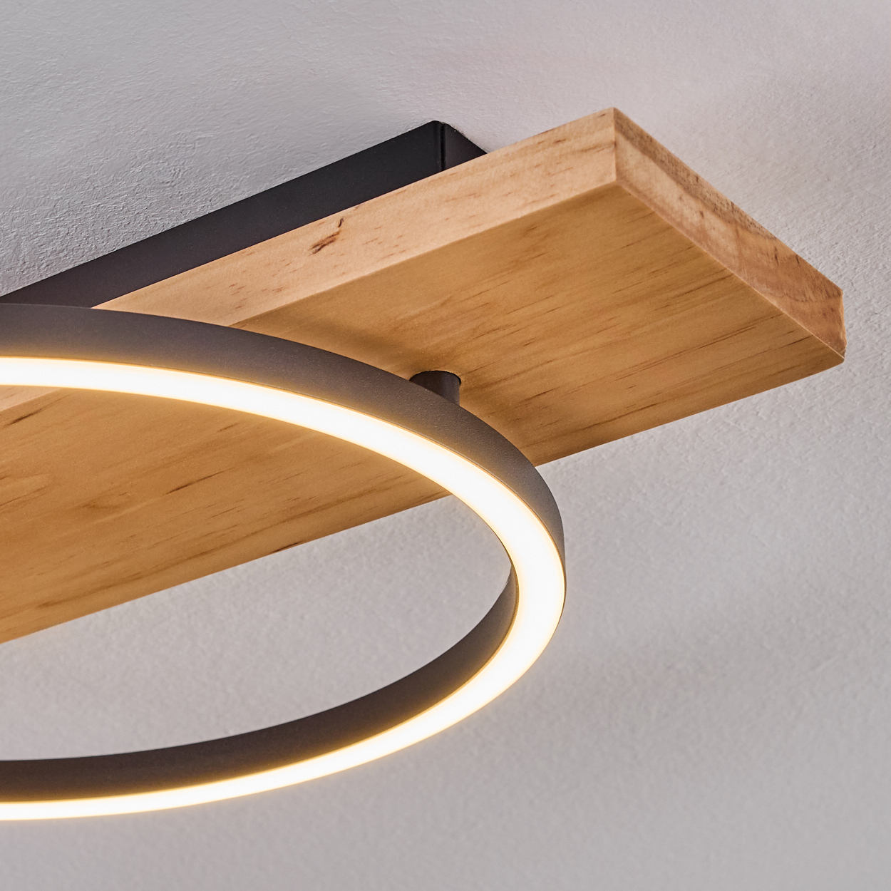Eine moderne Deckenleuchte. Sie hat einen Holzsockel mit schwarzem Metallträger. Unten befindet sich ein kreisförmiges Licht.