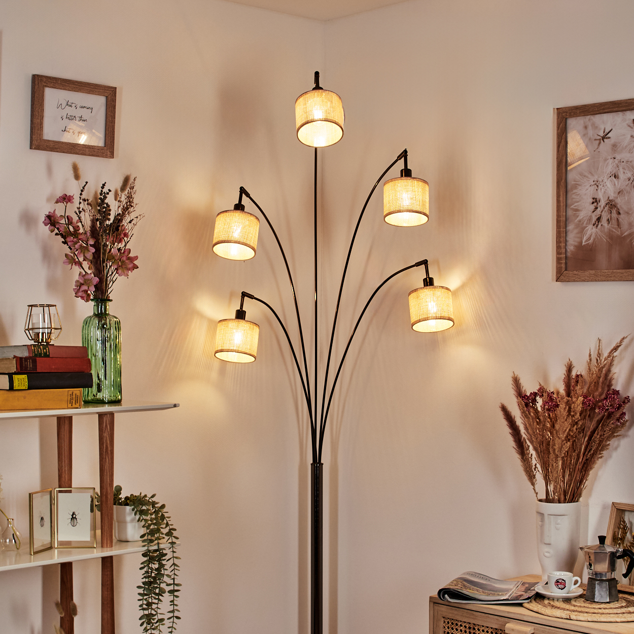 Eine Stehlampe mit f ünf Lichtern beleuchtet einen Raum. Dekorative Vasen, Rahmen, Bücher und Pflanzen sind darum platziert.