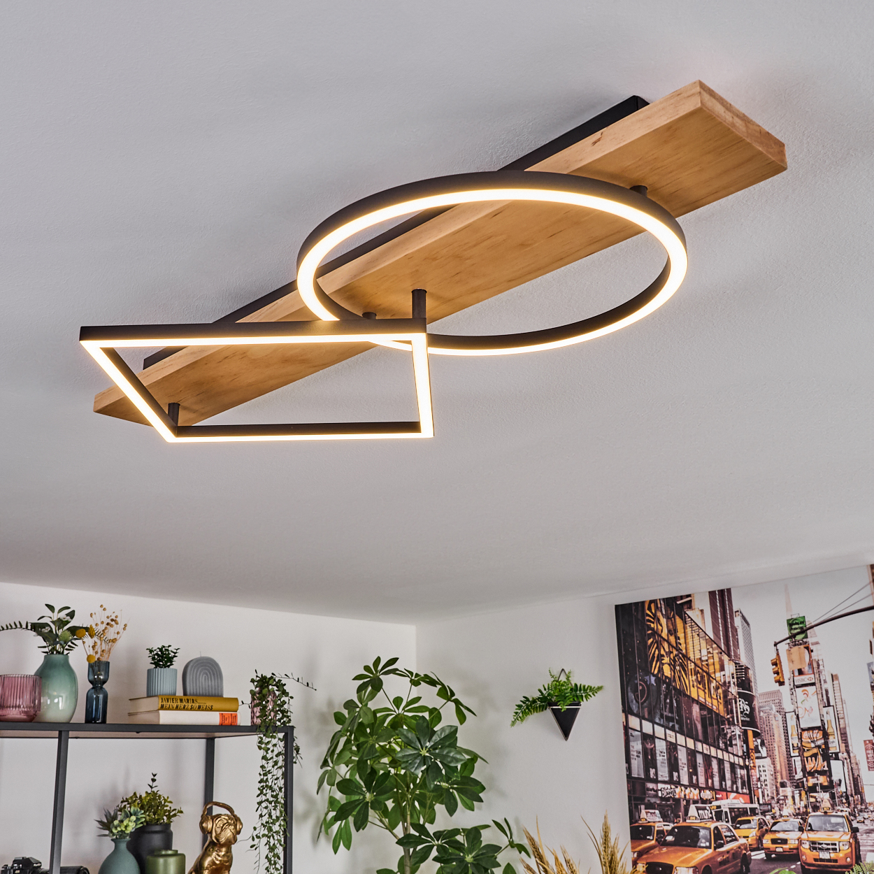 Eine moderne Deckenleuchte mit geometrischen Formen und Holzsockel. Im Hintergrund ein Regal mit Vasen und Pflanzen.