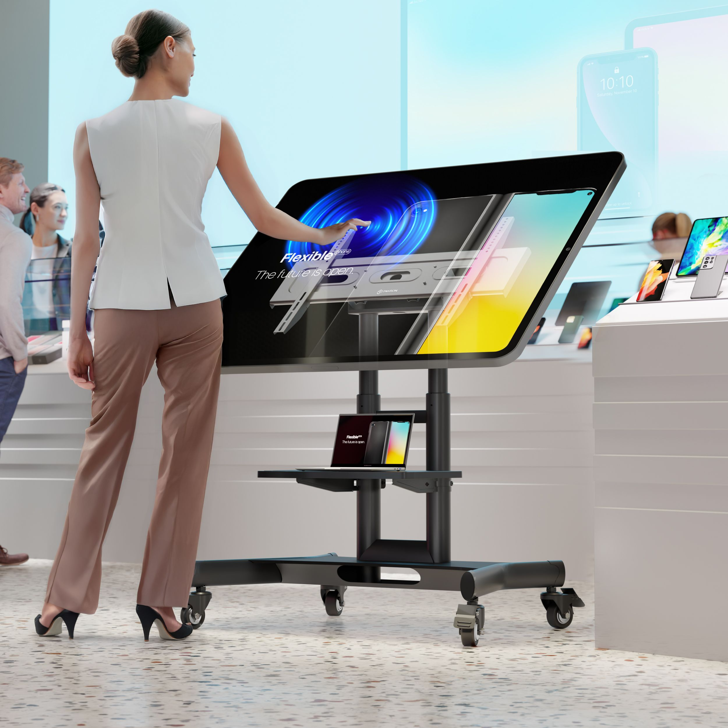 Kobieta dotyka dużego ekranu. Wyświetlacze obejmują telefony i tablety. Inni ludzie są w tle.