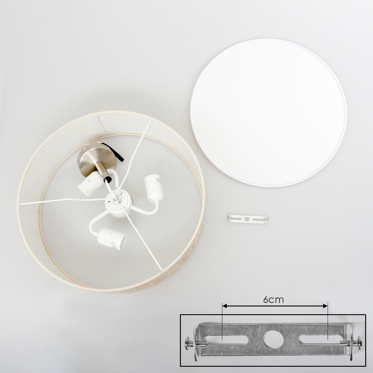 Draufsicht einer zerlegten Lampe. Komponenten: Lampenschirm, Deckenplatte, Metallhalterung und Lampenfassung.