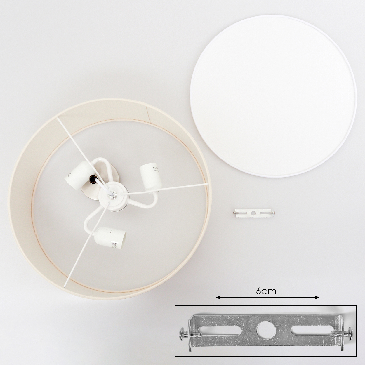 Draufsicht einer zerlegten Lampe. Zu den Teilen gehören ein Lampenschirm, eine weiße runde Abdeckung und Montagezubehör.