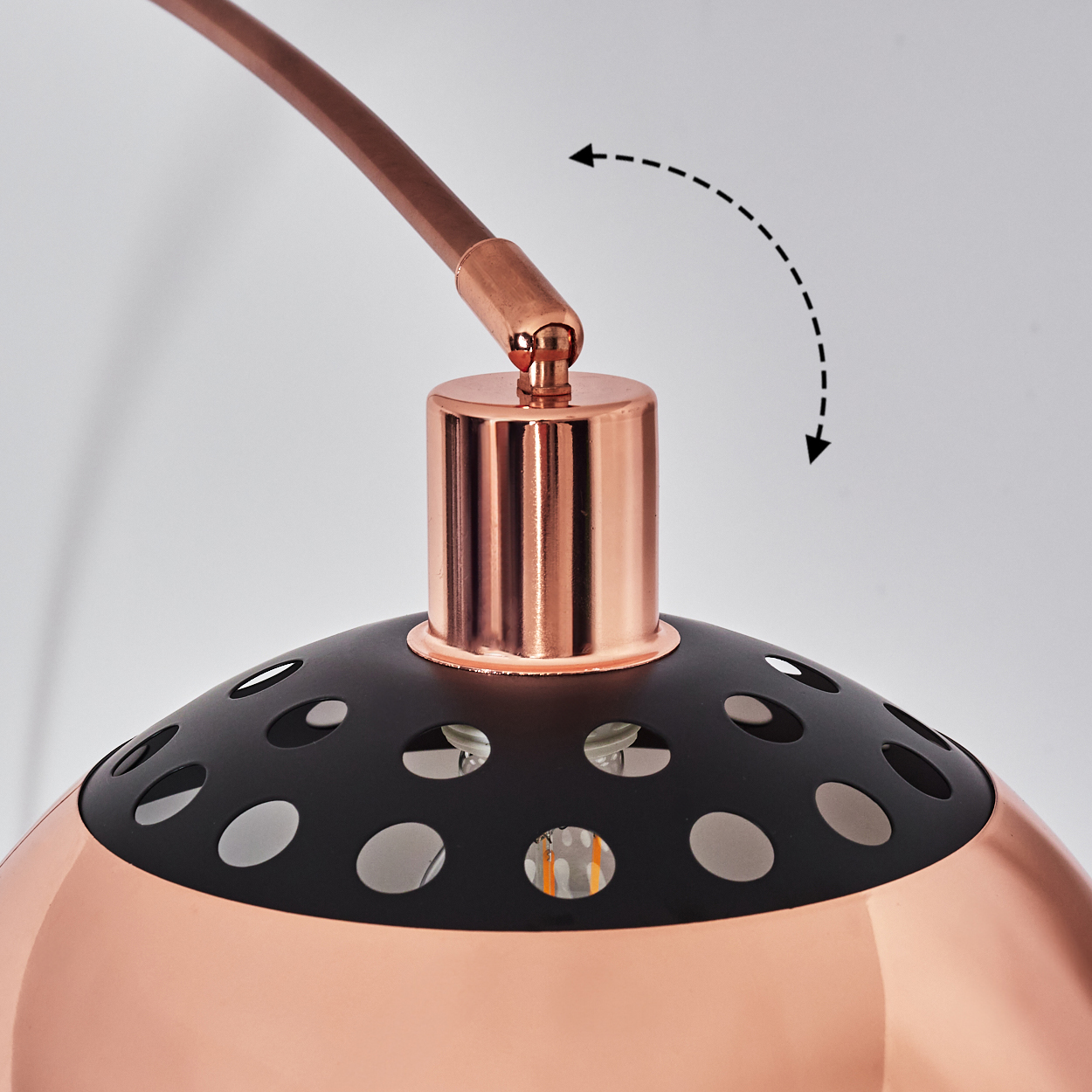 Nahaufnahme einer kupfer-schwarzen Lampe. Die Lampe hat einen gebogenen Arm und einen perforierten Schirm. Ein Pfeil zeigt die Verstellbarkeit an.