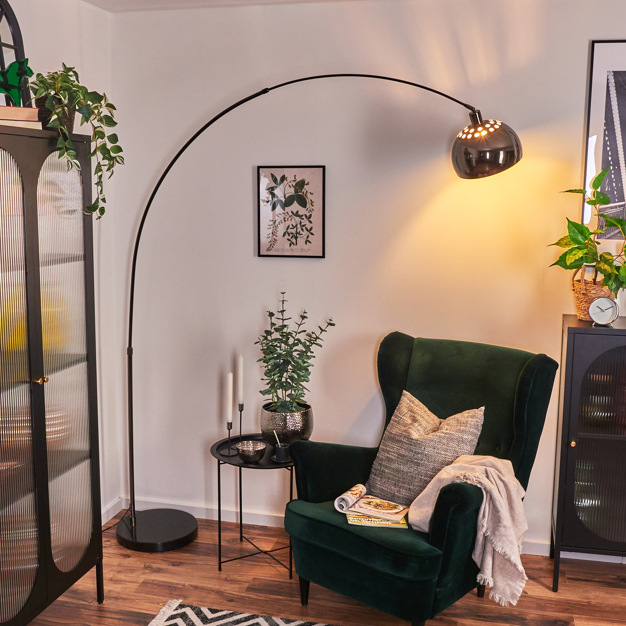 Ein dunkelgrüner Sessel mit Kissen und Decke, eine schwarze Lampe und ein kleiner Tisch daneben.