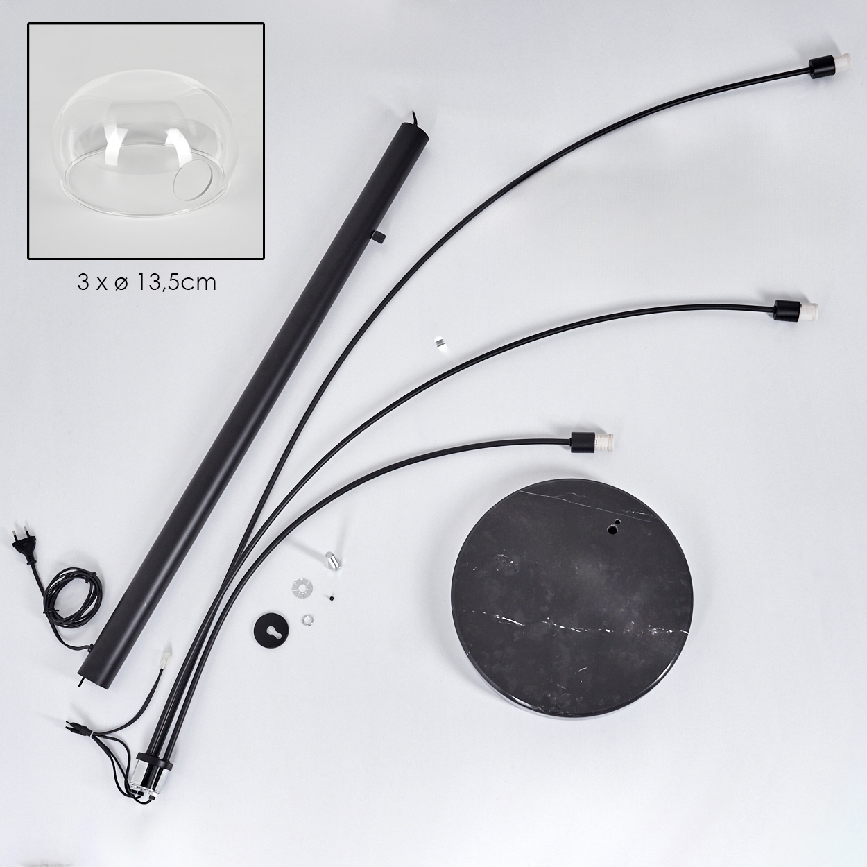 Zerlegte moderne Lampe. Enthält Glasschirm, schwarzes Metallgestell, Marmorsockel und diverse Hardware-Komponenten auf weißer Oberfläche.