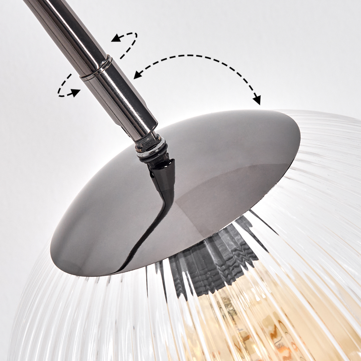 Nahaufnahme einer modernen Lampe. Ein Chromarm ist an einem Lampenschirm aus Glas mit vertikalen Rillen befestigt. Pfeile zeigen die einstellbare Richtung an.