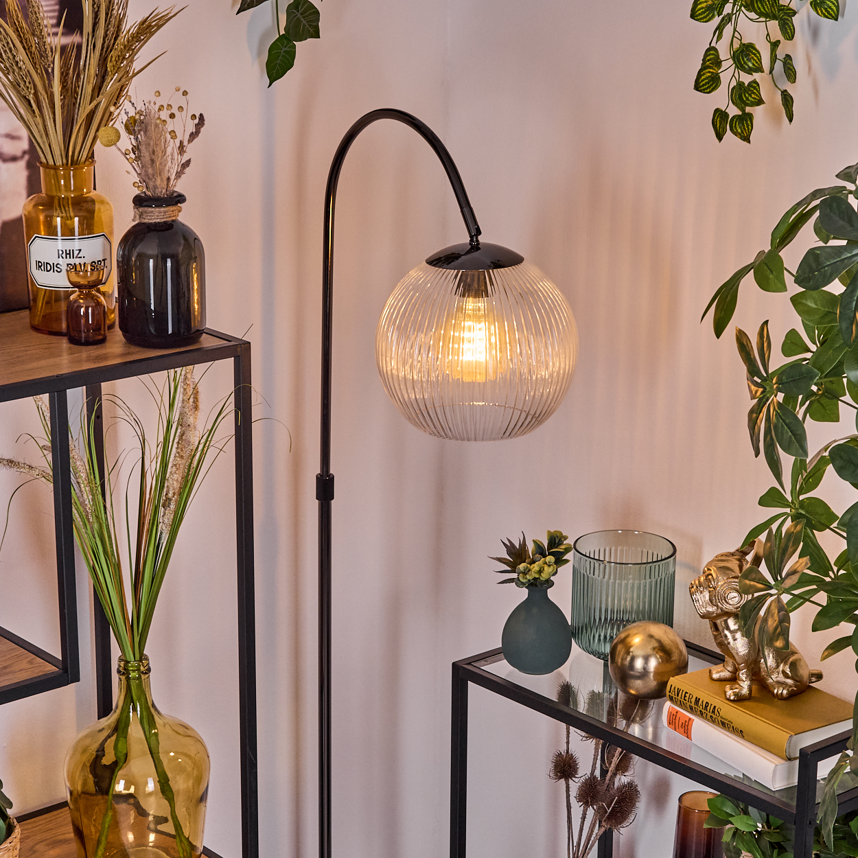 Moderne Innenszene mit Stehlampe, Dekor, Vasen und Pflanzen. Eine goldene Hundestatue steht auf einem Regal mit Büchern.