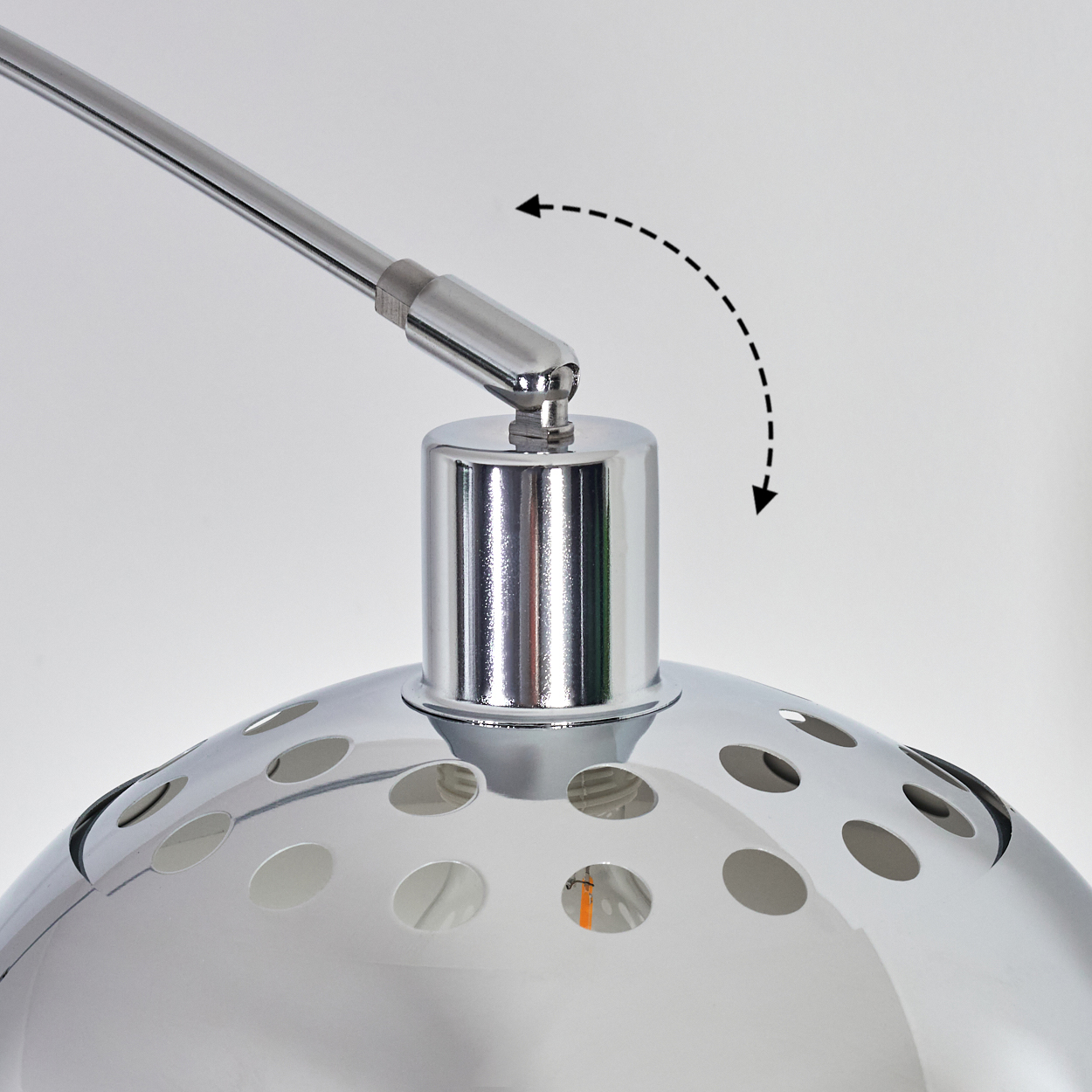 Nahaufnahme einer Chromlampe. Der Lampenkopf hat Löcher. Ein Pfeil zeigt den verstellbaren Arm der Lampe an.