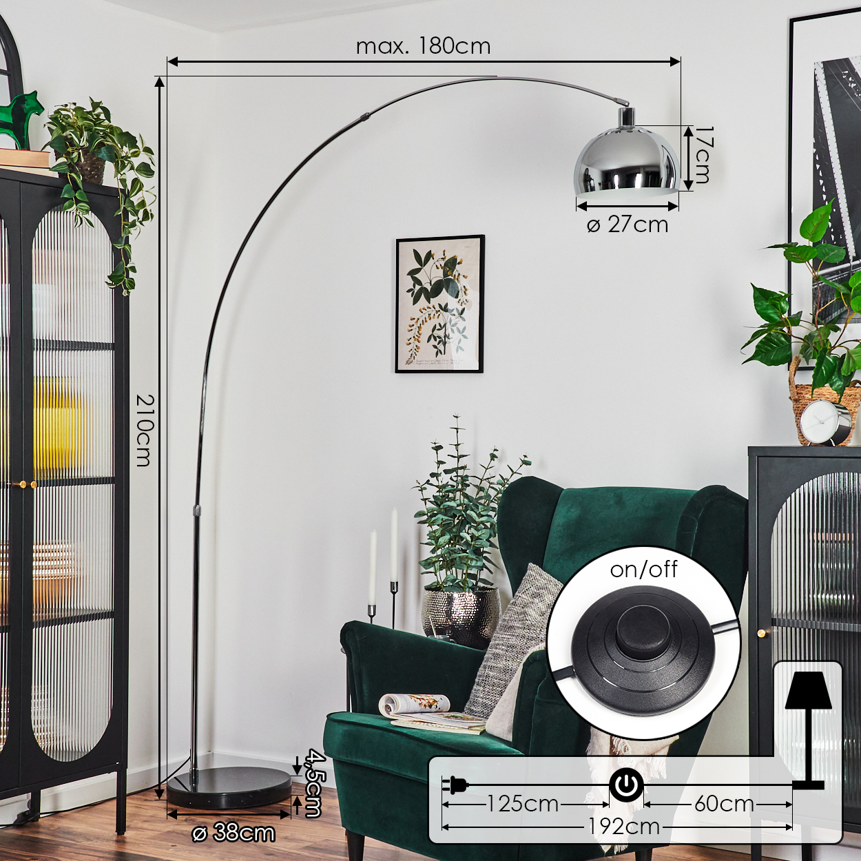 Eine moderne Bogenstehlampe steht neben einem grünen Sessel. Sie hat eine Chromoberfläche und einen runden Sockel. Die Lampe steht an einer weißen Wand.