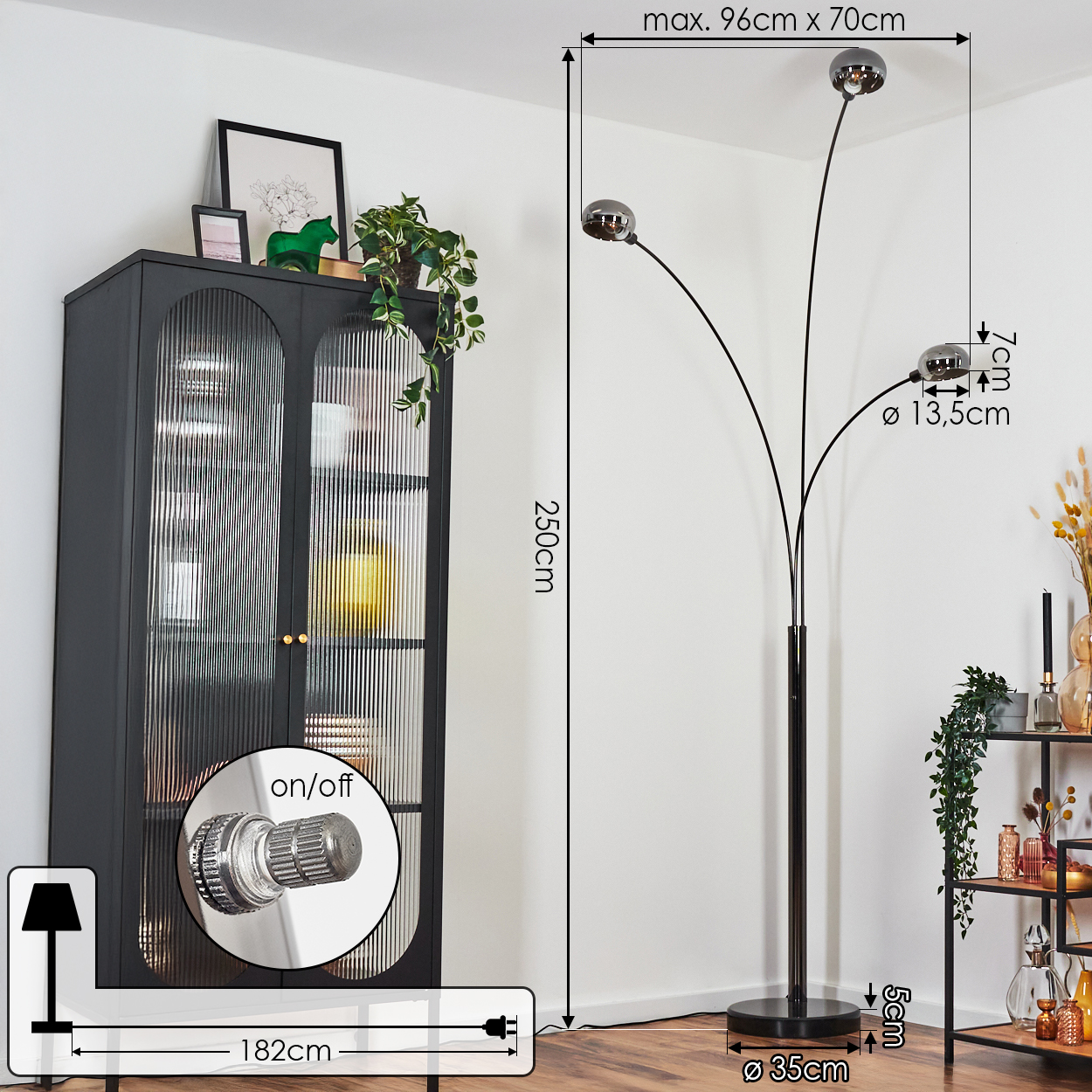 Ein Raum mit einem schwarzen Schrank, einer schwarzen Stehlampe mit drei Lampen und einem Regal mit Dekorationen.