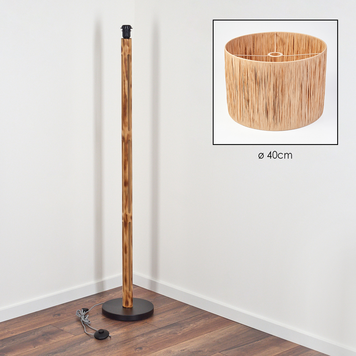 Eine Stehlampe mit Holzstange, schwarzem Fuß und Lampenschirm in separatem Rahmen. Der Schirm ist zylindrisch und aus gewebtem Material.