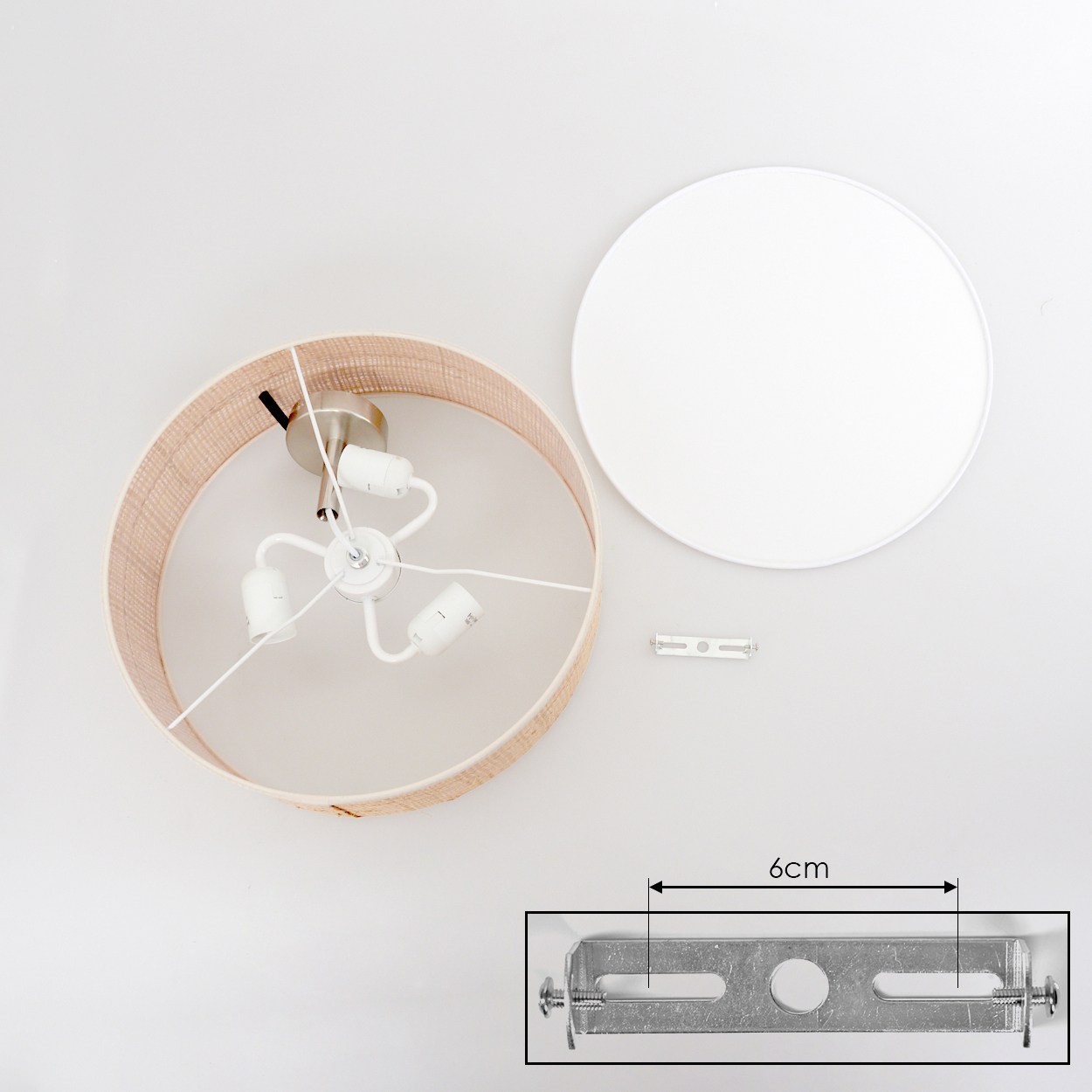 Draufsicht auf eine zerlegte Lampe. Der beigefarbene Lampenschirm, die weiße Basis und die Montagehardware sind sichtbar. Der Hintergrund ist weiß.