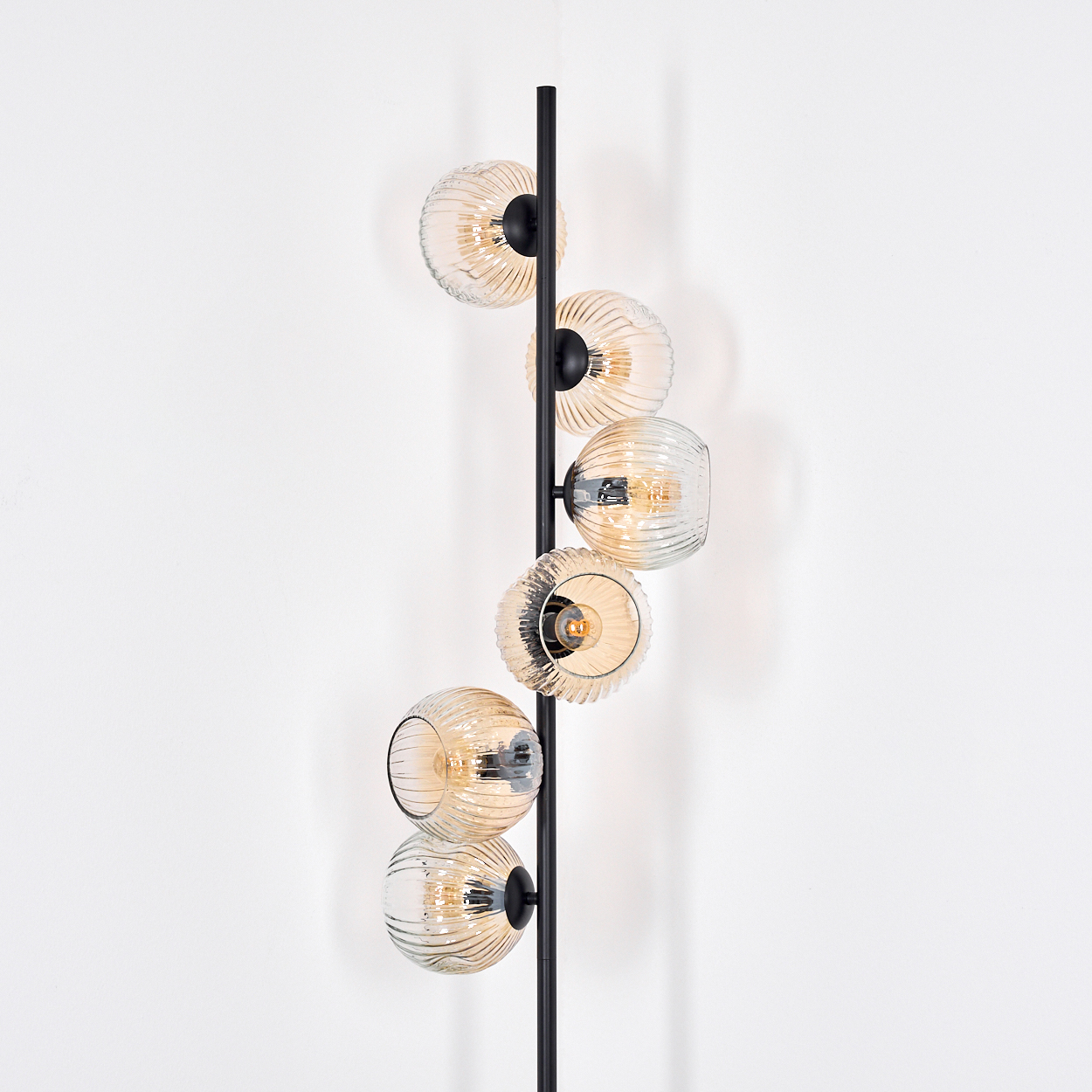 Eine moderne Stehlampe mit sechs Glasschirmen in verschiedenen Bernsteintönen. Die Lampe hat ein schwarzes Metallgestell.