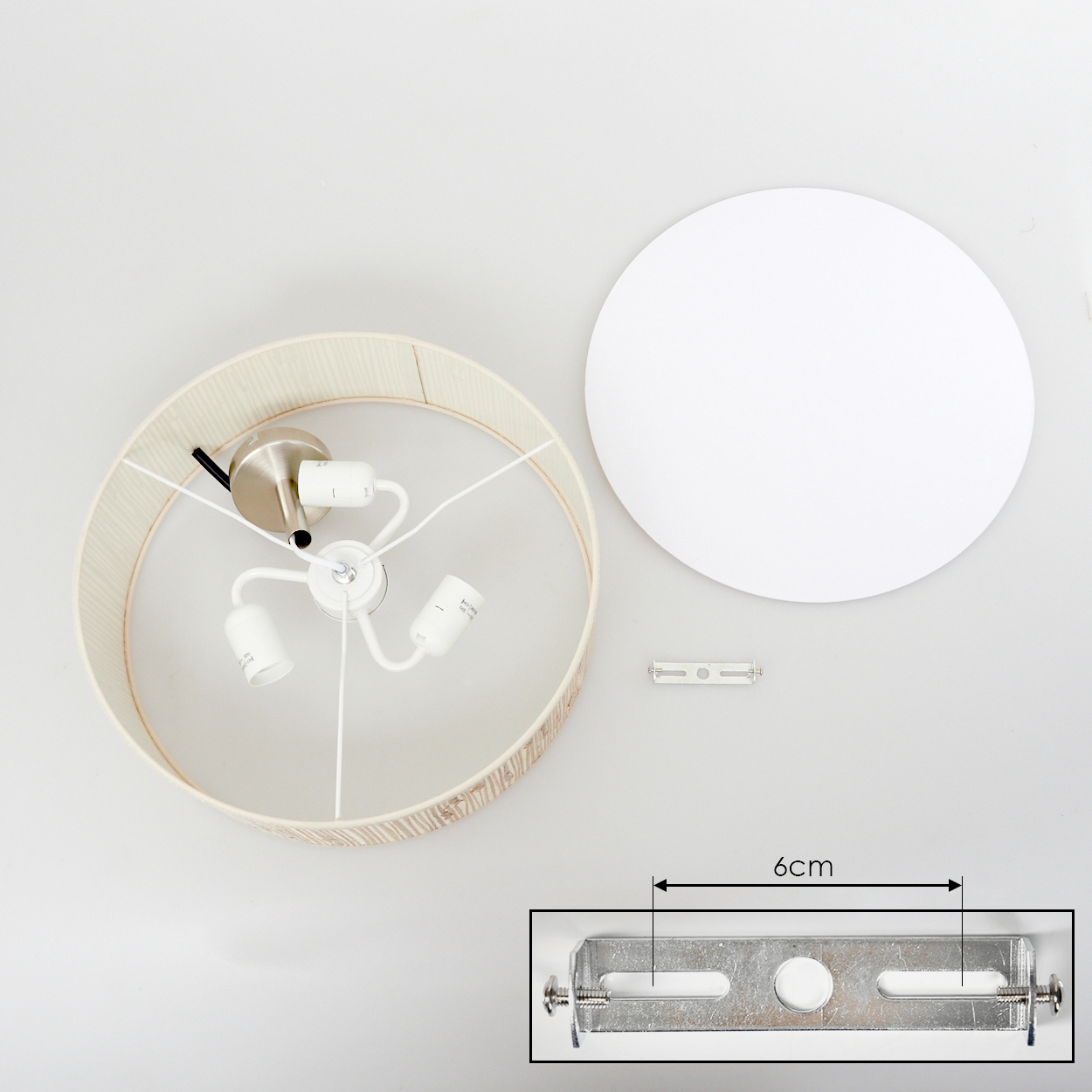 Draufsicht einer zerlegten Lampe. Sie zeigt den Schirm, die Leuchte, die Montagehardware und eine weiße runde Basis vor weißem Hintergrund.