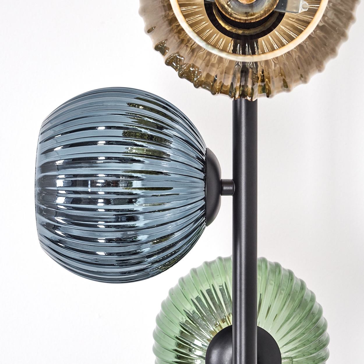 Moderne Lampe mit drei Glasschirmen in Blau, Grün und Braun. Schwarzer Metallrahmen. Weißer Hintergrund.