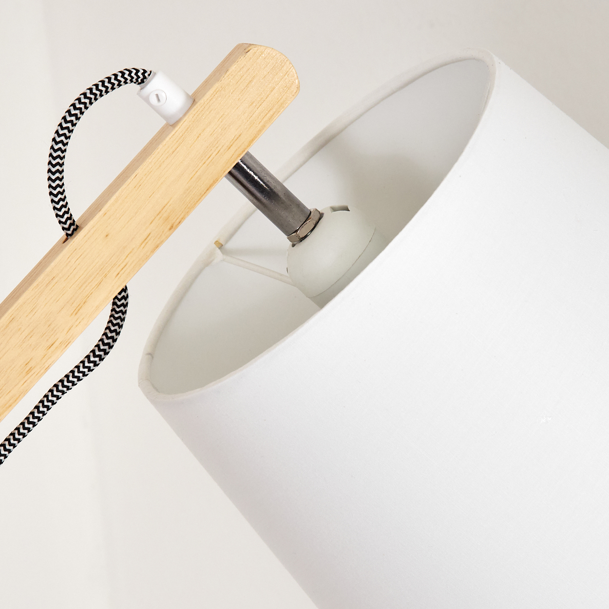 Nahaufnahme eines weißen Lampenschirms mit Holzstütze und einem schwarz-weiß gestreiften Kabel. Der Hintergrund ist weiß.