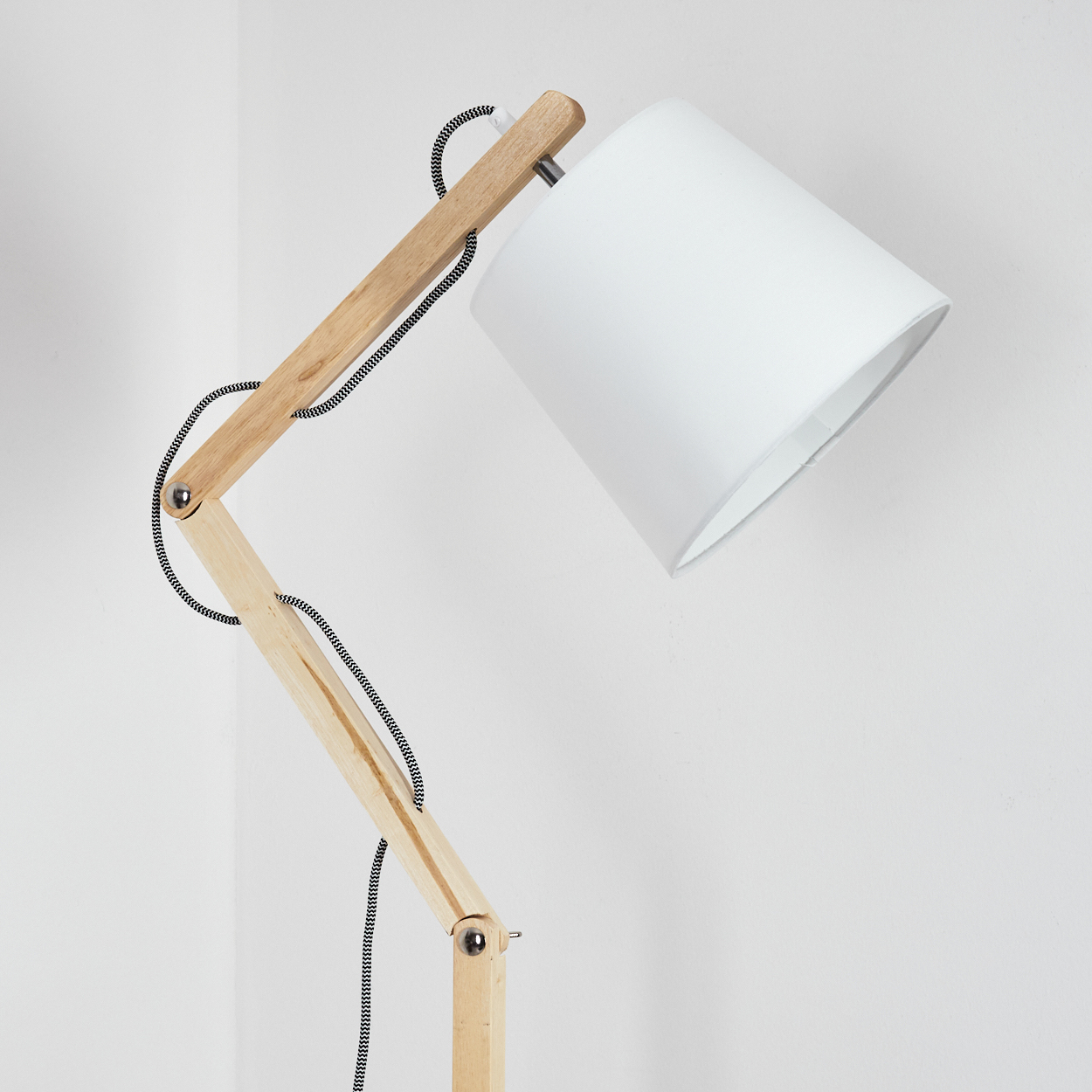 Eine moderne Stehlampe aus Holz mit weißem Lampenschirm. Die Lampe hat einen flexiblen Arm und eine schwarz-weiß gestreifte Schnur.