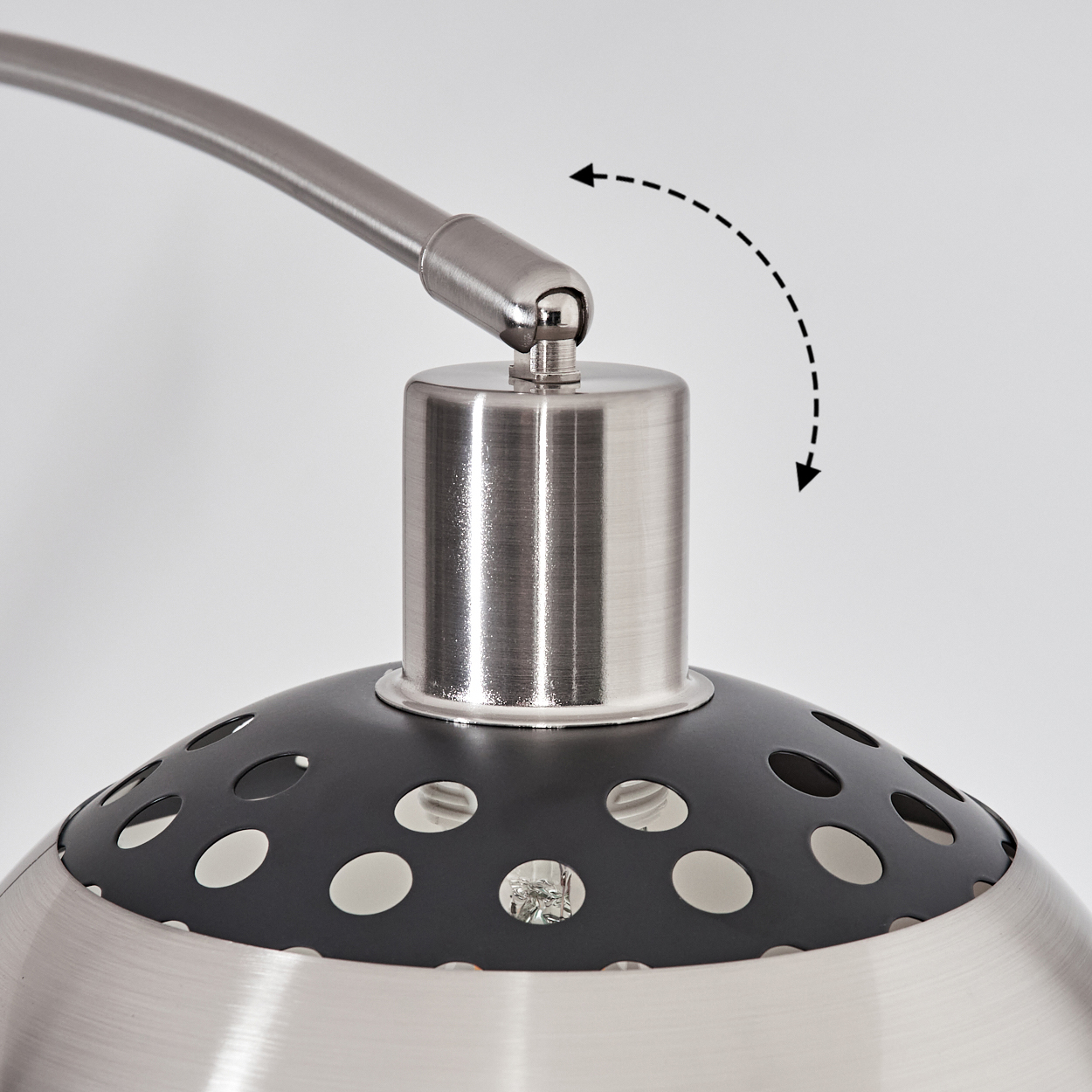 Nahaufnahme einer Lampe. Metallteile. Ein schwarzer Schirm mit Löchern. Ein Pfeil zeigt die Bewegung.