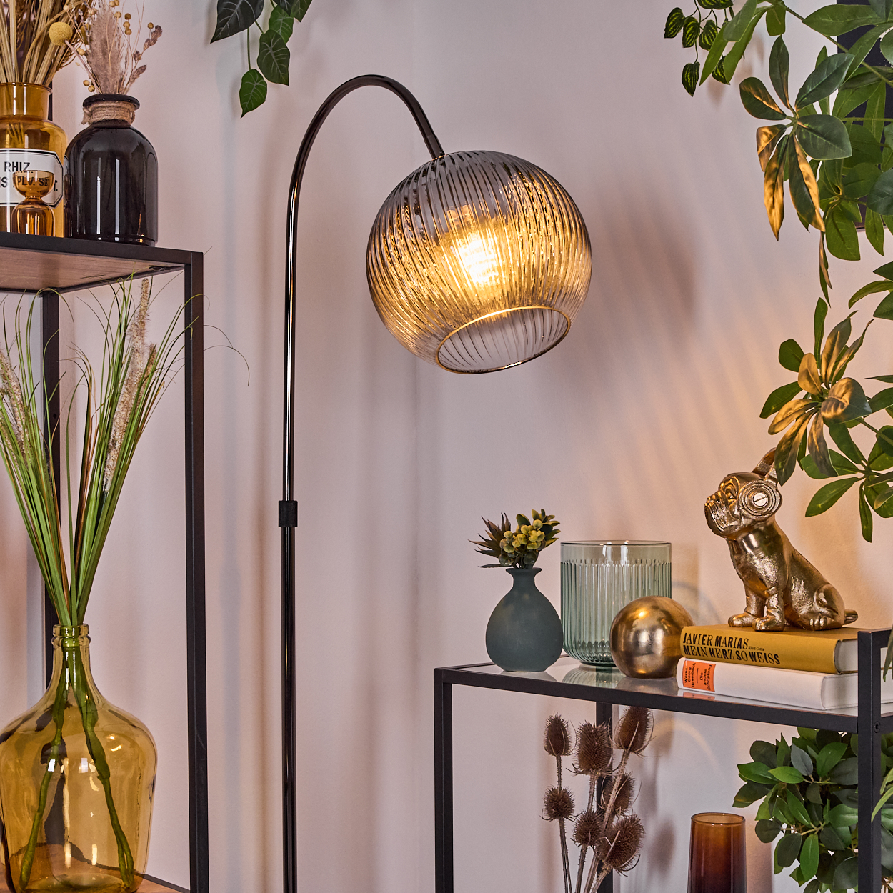 Ein modernes Interieur mit einer Stehlampe und Regalen. Vasen mit Pflanzen und Dekorationen stehen auf den Regalen. Eine goldene Bulldoggenstatue ist ebenfalls zu sehen.