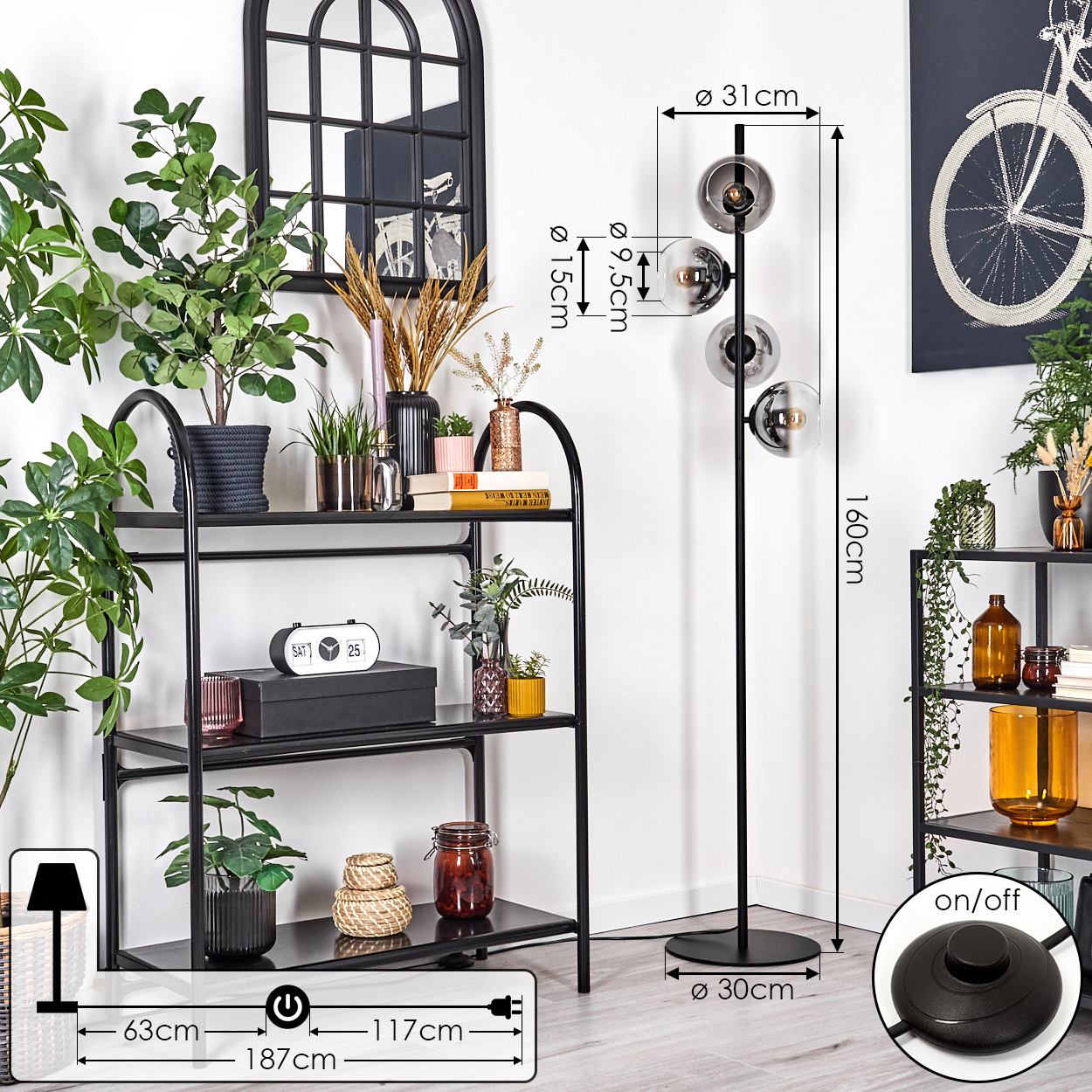 Ein Raum mit einem schwarzen Regal, einer Stehlampe und einem Fahrradbild. Pflanzen und Dekorationsartikel stehen auf dem Regal.
