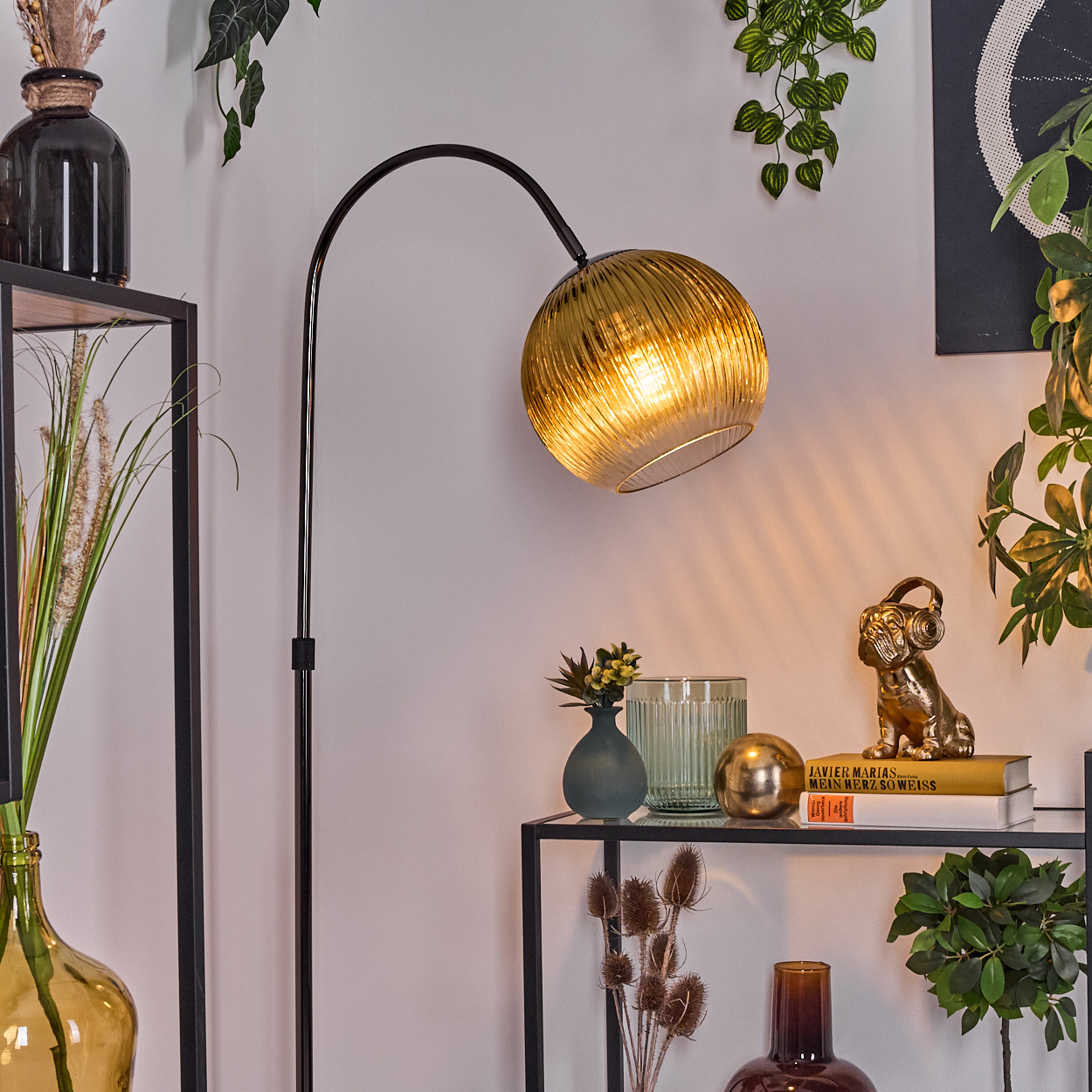 Ein Raum mit goldener Lampe, Regalen mit Vasen, Pflanzen und einer Hundestatue mit Kopfhörern.