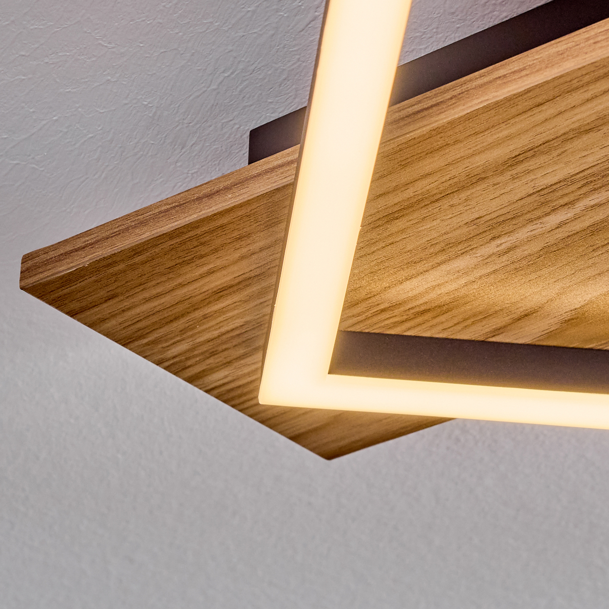 Moderne Deckenleuchte. Sie hat einen Holzsockel mit einem hellen, rechteckigen Lichtrahmen. Der Hintergrund ist eine weiße Decke.