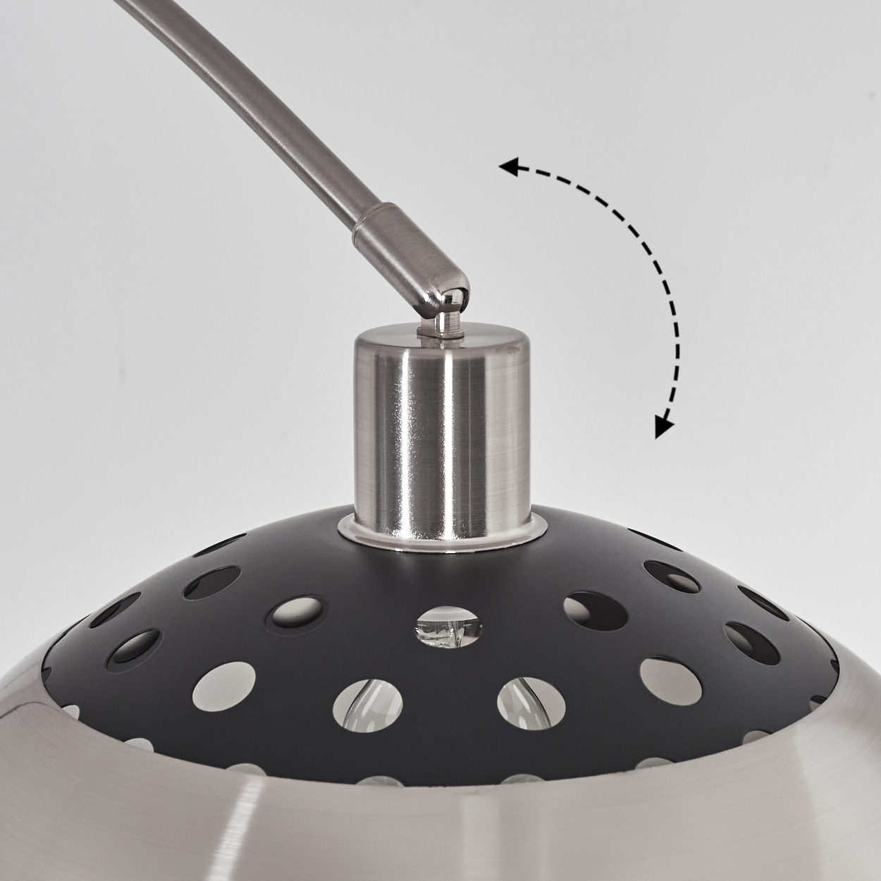 Nahaufnahme einer modernen Lampe. Sie hat einen silbernen Sockel, einen schwarzen perforierten Schirm und einen silbernen Schwenkarm. Weißer Hintergrund.
