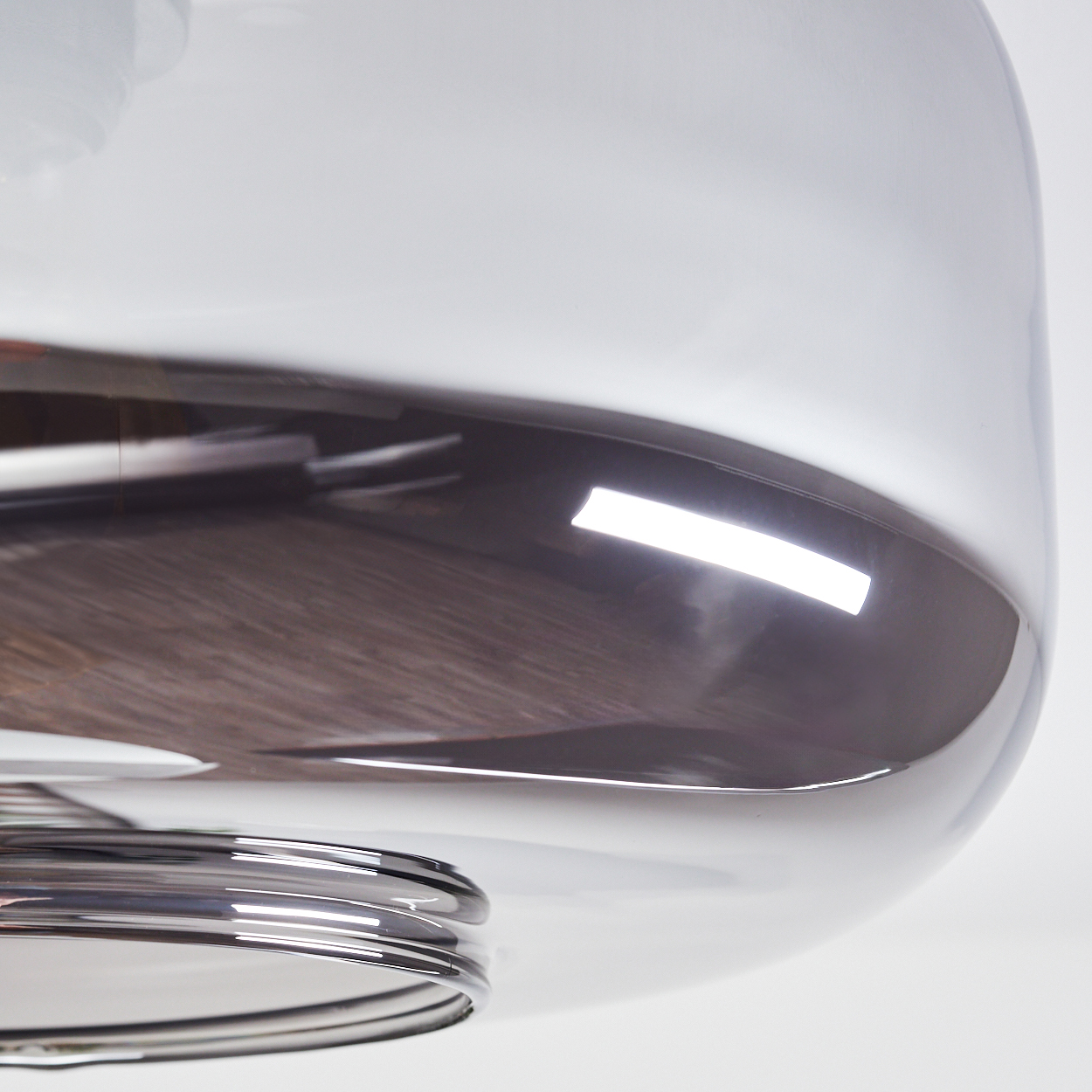 Nahaufnahme einer modernen Lampe. Sie hat einen runden Glasschirm mit reflektierender Oberfläche. Der Sockel ist ein Silberring.