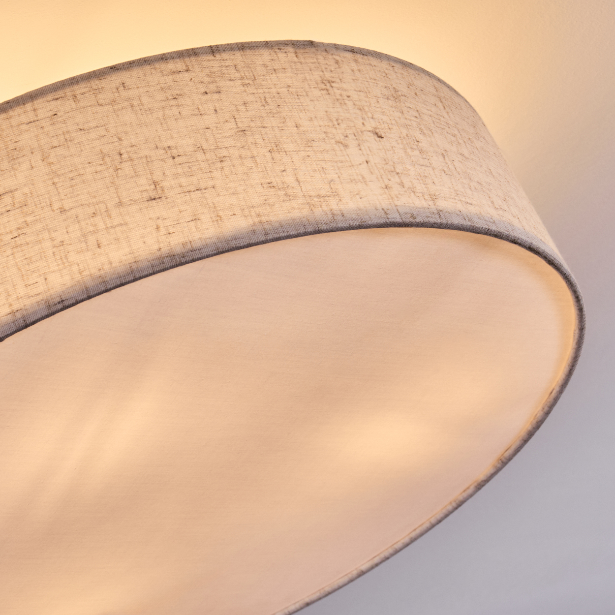 Nahaufnahme eines Lampenschirms. Der Lampenschirm ist grau und weiß, mit gebogenem Design. Der Hintergrund ist ein Weiß-Gelb-Gradient.