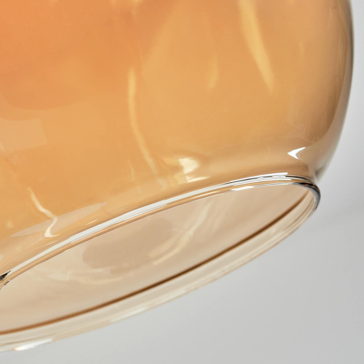 Nahaufnahme eines Glasobjekts, bernsteinfarben, mit klarem Rand. Der Hintergrund ist ein weiches Weiß, das das Glas hervorhebt.