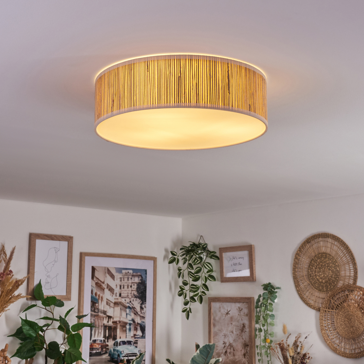 Eine runde Deckenlampe mit gewebter Textur hängt über einem Raum mit gerahmter Kunst und Pflanzen.