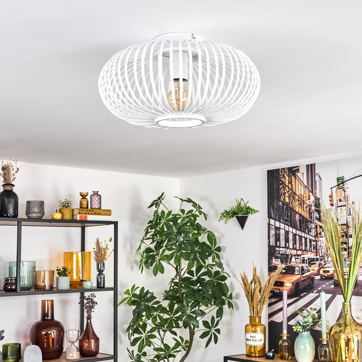 Weiße Deckenlampe. Regale mit Vasen und Dekorationen. Eine große Pflanze. Ein New York City Bild an der Wand.