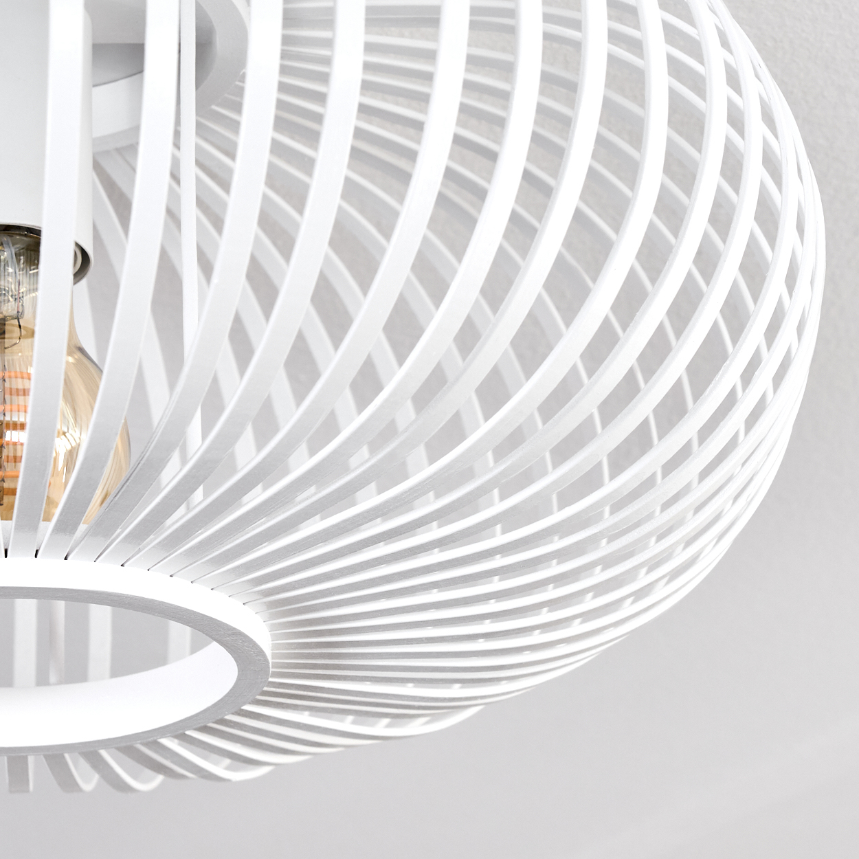 Eine weiße, kugelförmige Lampe mit Spiralmuster. Die Glühbirne ist sichtbar. Der Hintergrund ist eine weiße Decke.