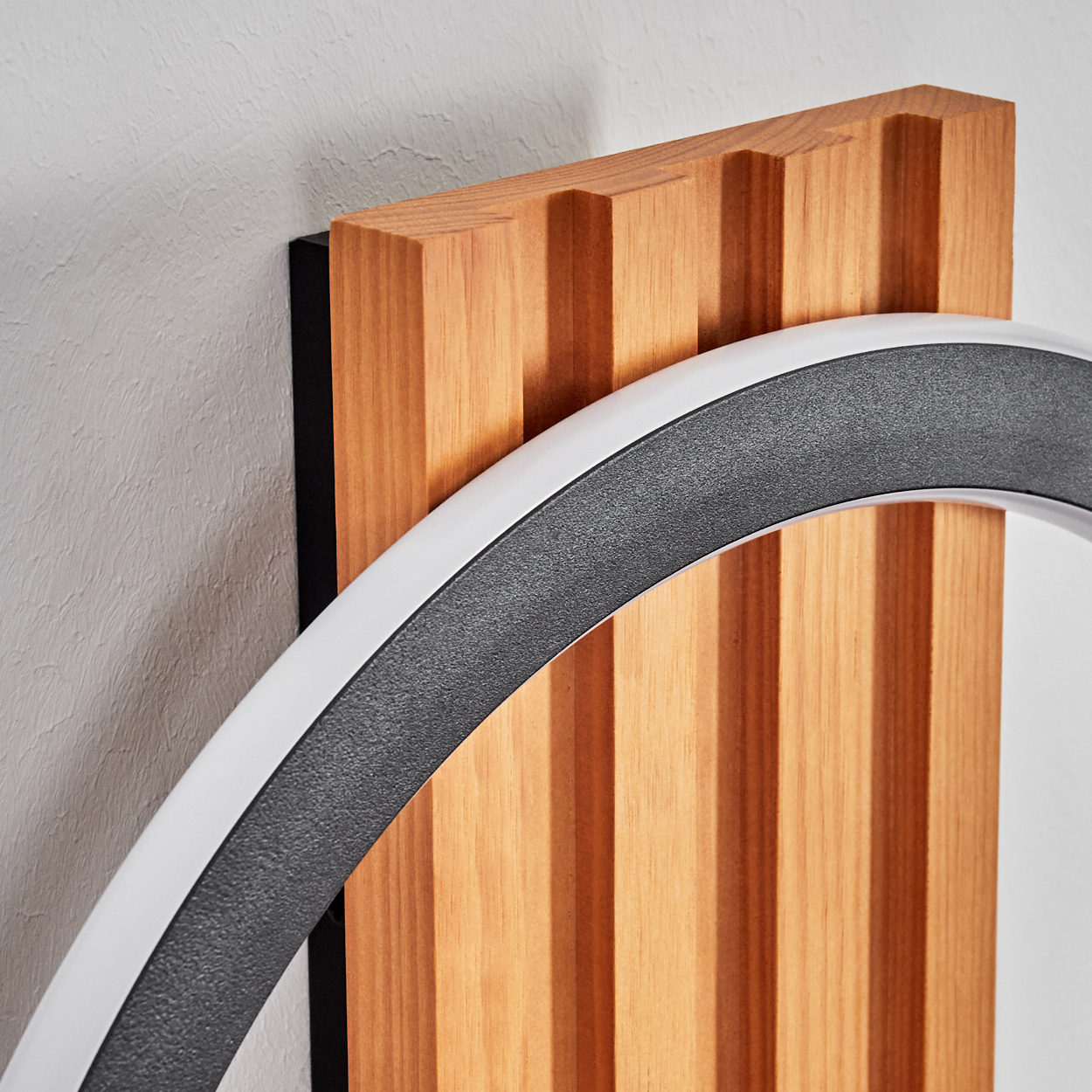 Eine moderne Wandlampe. Sie hat eine Holzverkleidung mit vertikalen Rillen. Ein Halbkreislicht befindet sich vorne, mit weißen und dunkelgrauen Farben.