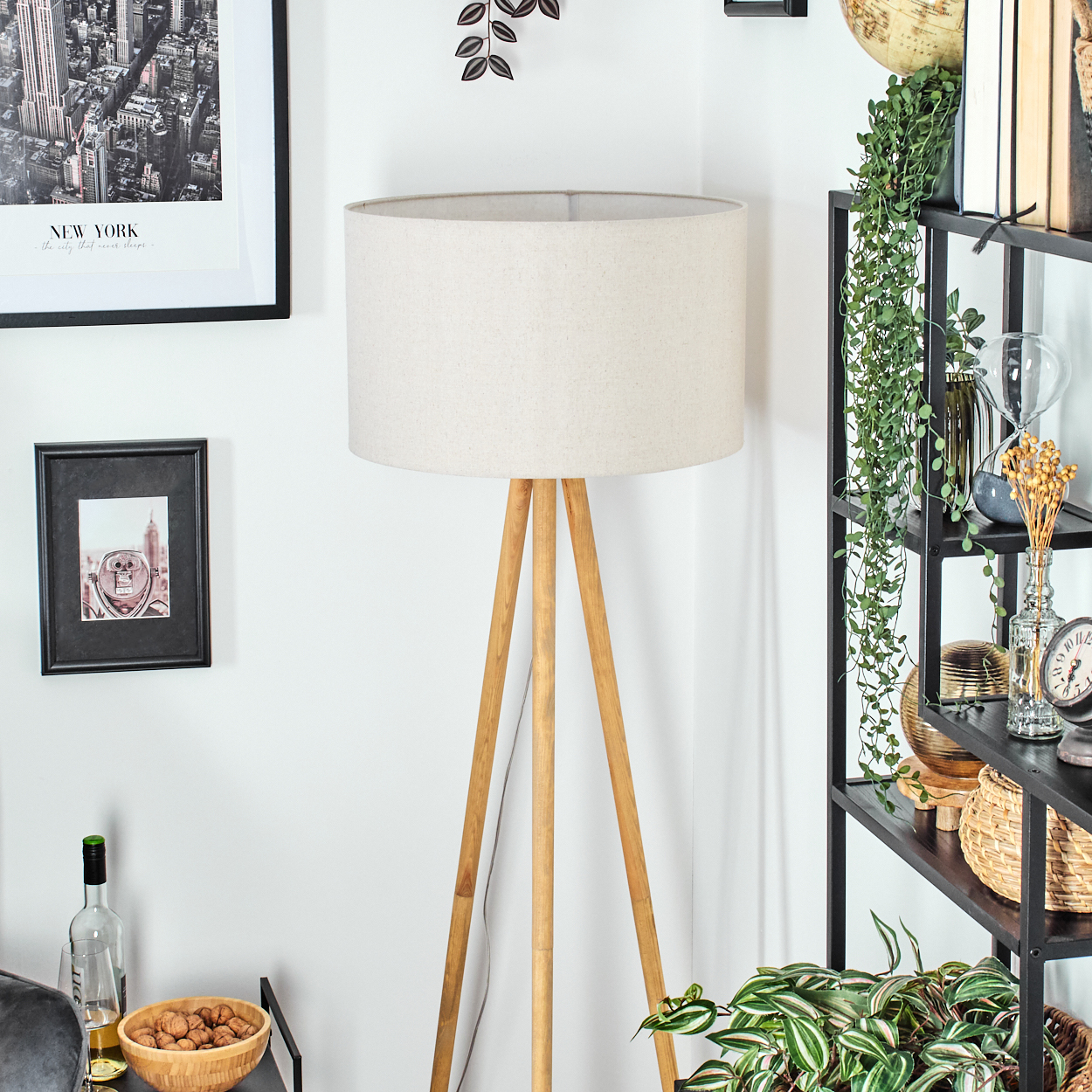 Ein Raum mit einer Holzlampe, einem New York-Bild, einem Regal mit Pflanzen und einer Schale mit Walnüssen. Die Lampe ist im Fokus.