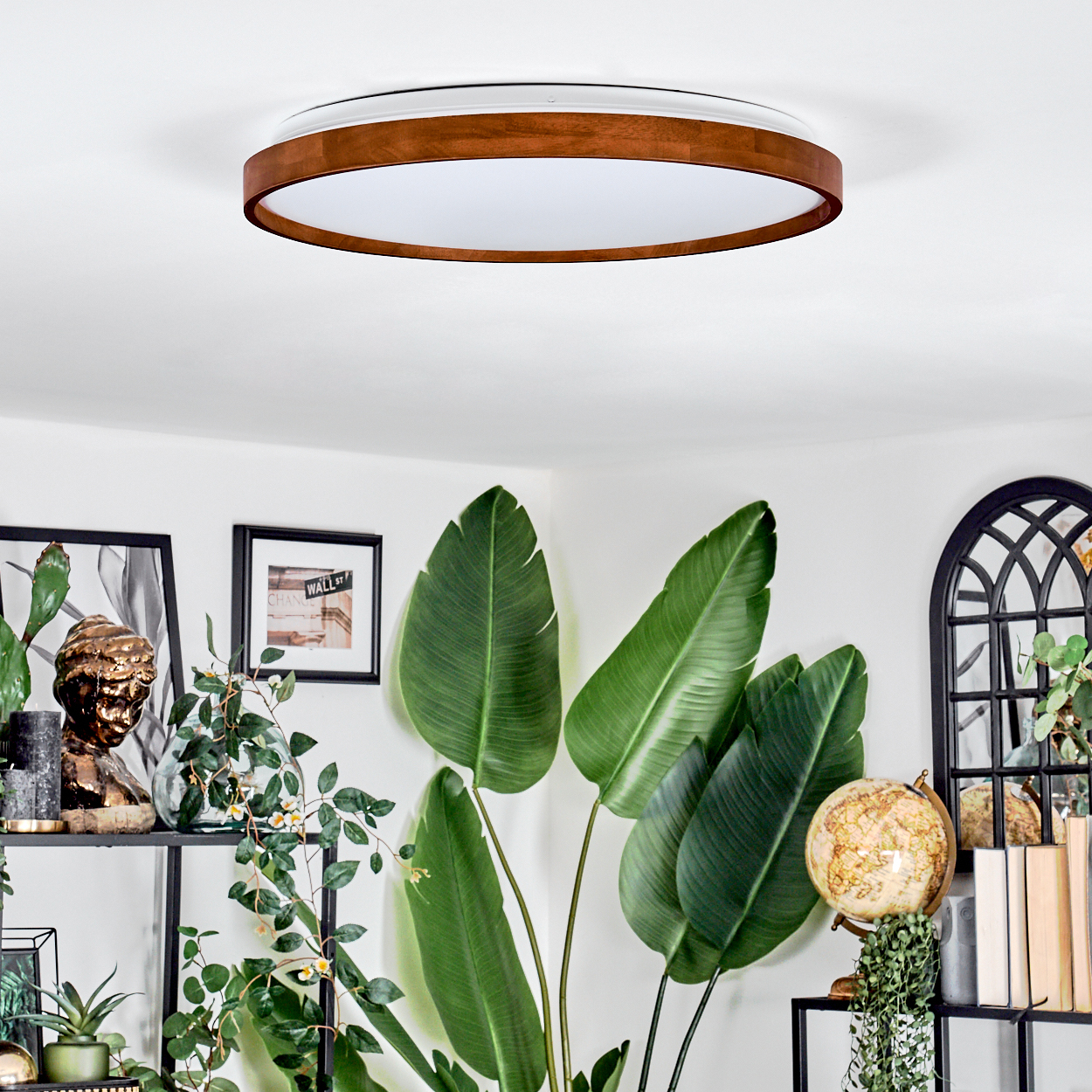 Ein modernes Wohnzimmer mit brauner und weißer Deckenleuchte, großen grünen Pflanzen und einem Globus.