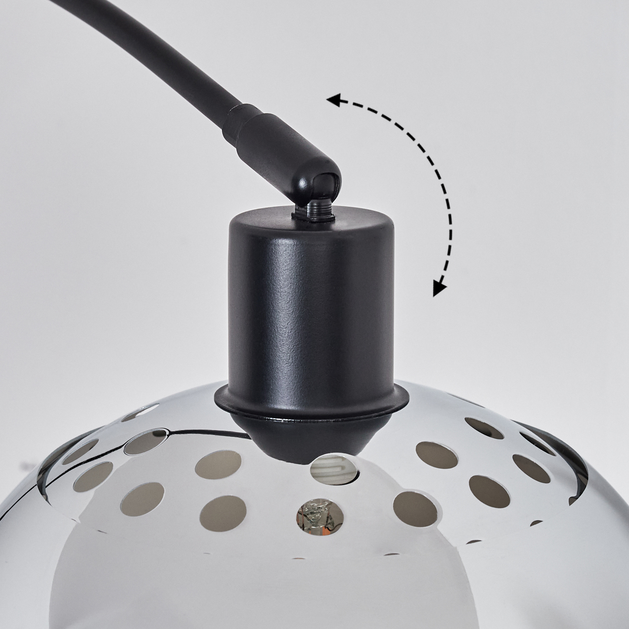 Nahaufnahme einer schwarzen Lampe. Ein gebogener Arm verbindet sich mit einem kreisförmigen Lampenschirm mit Perforationen. Pfeile zeigen den verstellbaren Kopf der Lampe an.