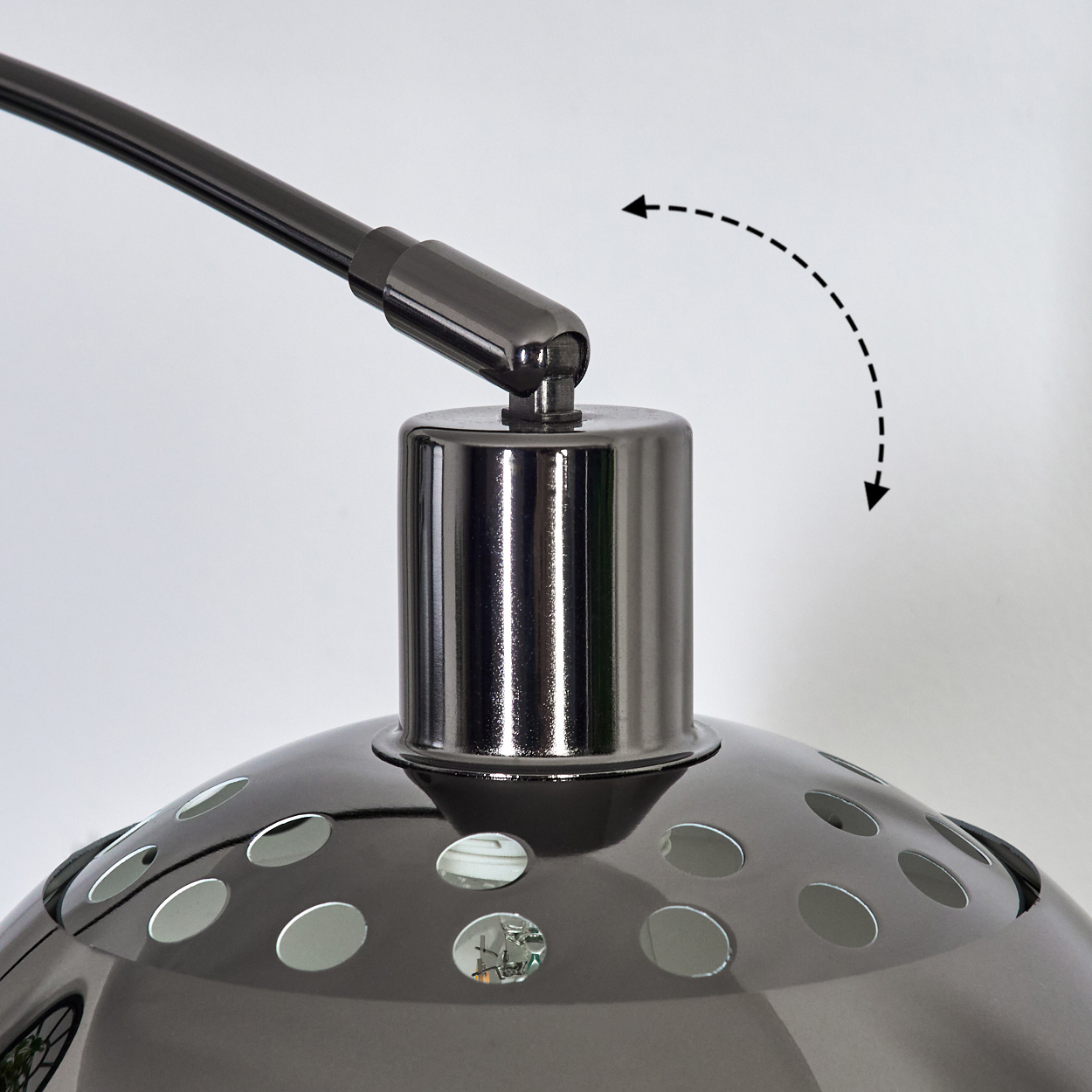 Nahaufnahme einer dunkelgrauen Lampe mit rundem Schirm und Löchern. Der Arm der Lampe ist verstellbar. Weißer Hintergrund.