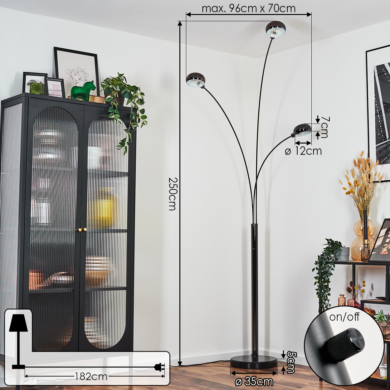 Eine moderne schwarze Stehlampe mit drei Lichtern, neben einem schwarzen Schrank und anderen Dekorationen.