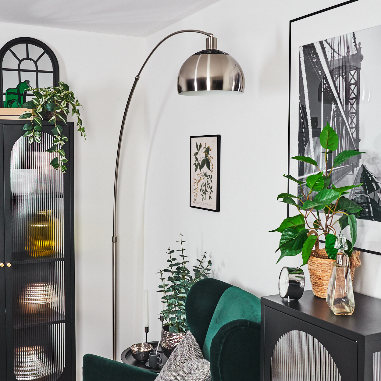 Ein modernes Wohnzimmer mit grünem Samtstuhl, Pflanzen, Stehlampe und schwarzem Schrank mit Dekoration und Stadtbild.