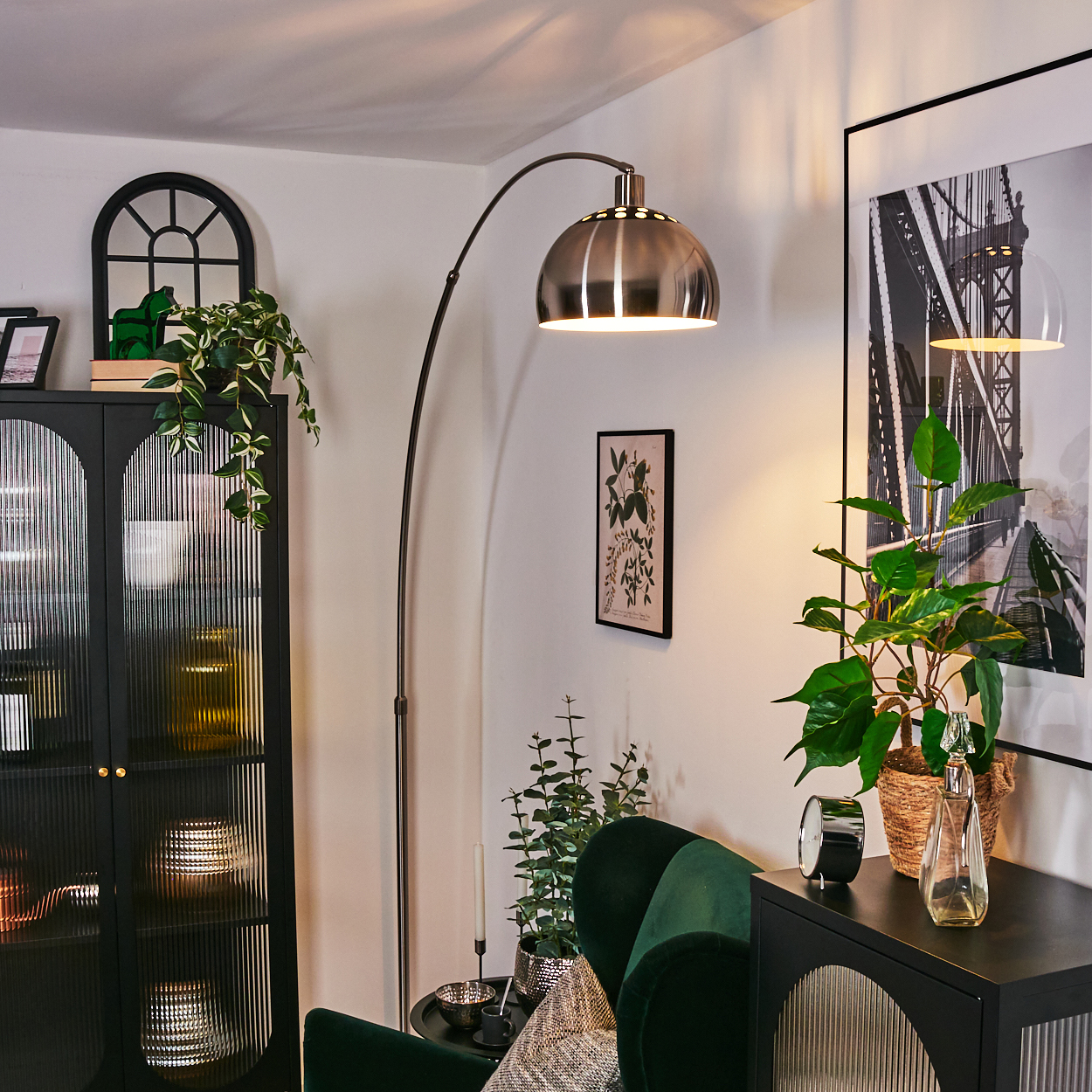Ein modernes Wohnzimmer mit einer großen Bogenlampe, einem grünen Sessel und einem schwarzen Schrank mit Pflanzen und Kunstwerken.