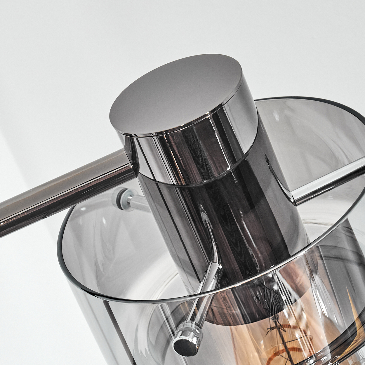 Nahaufnahme einer modernen Lampe. Eine zylindrische Metallstruktur ist in Glas eingeschlossen, alles vor weißem Hintergrund.
