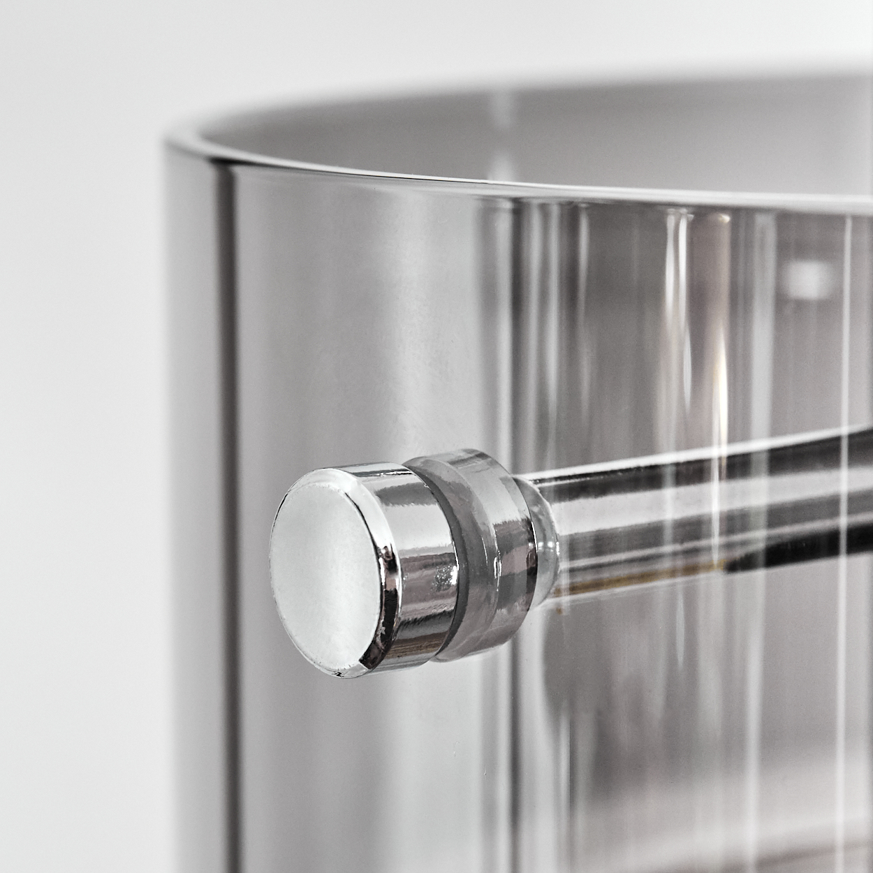 Nahaufnahme eines glänzenden, silbernen Metallbehälters mit Griff. Der Griff ist ebenfalls silber und reflektiert das Licht. Der Hintergrund ist weiß.