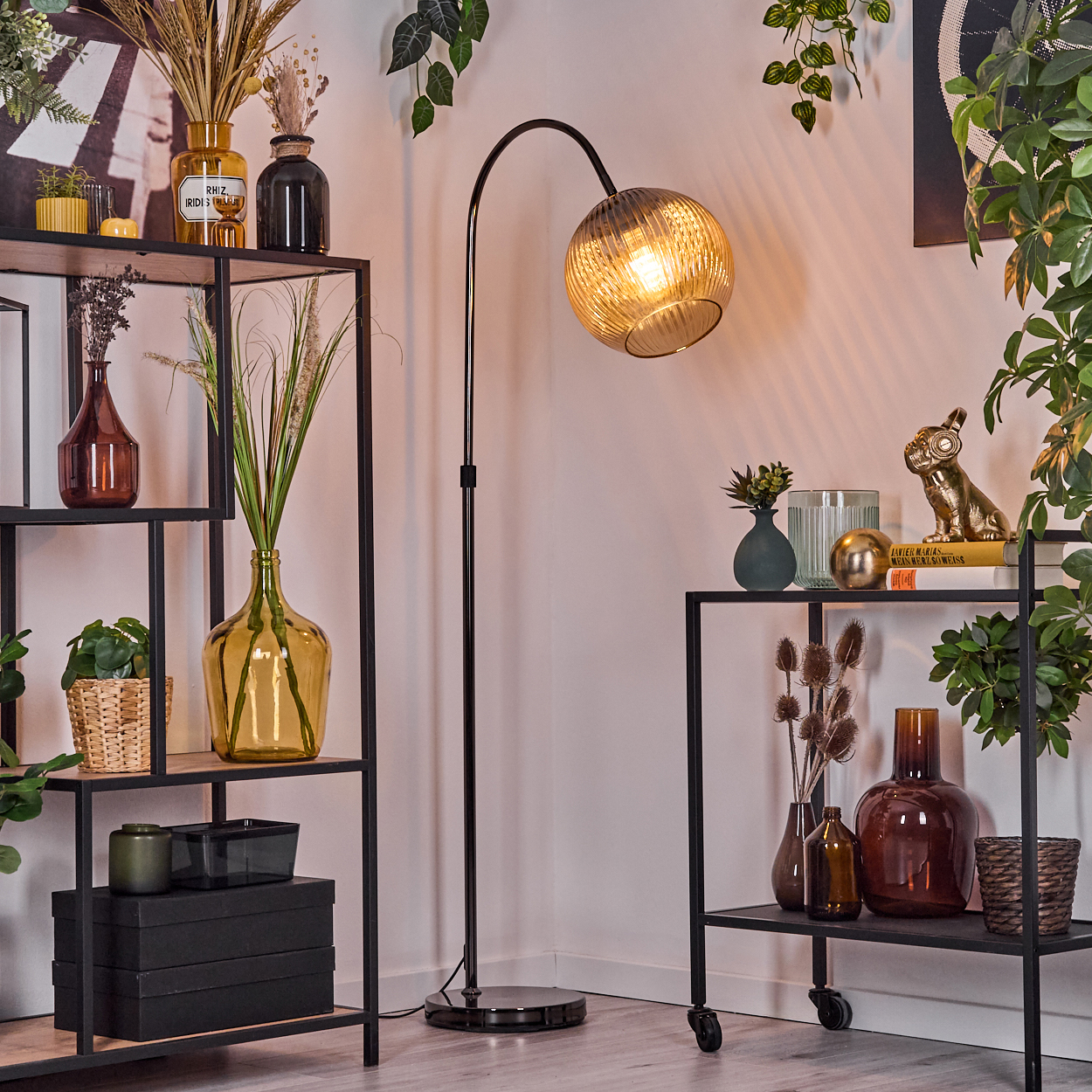 Eine Zimmerecke mit Regalen, einer Stehlampe und Pflanzen. Regale halten Vasen, Pflanzen und Dekor. Die Lampe hat einen kugelförmigen Schirm.