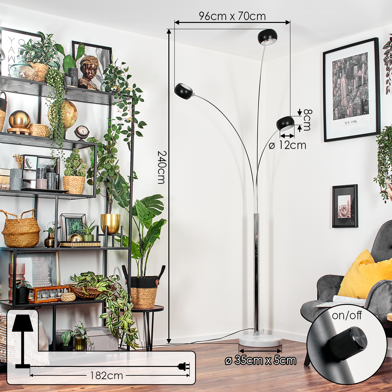 Eine moderne Stehlampe mit drei schwarzen Lampenschirmen, Pflanzen und einem schwarz gerahmten Bild im Hintergrund, neben einem grauen Sessel.