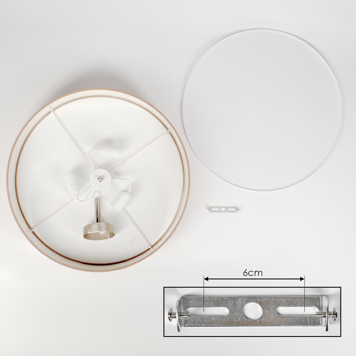 Draufsicht auf eine zerlegte Lampe. Zu den Komponenten gehören ein Lampenschirm, ein weißes Kreisteil und eine Metallhalterung. Eine Nahaufnahme zeigt die Halterungsabmessungen.