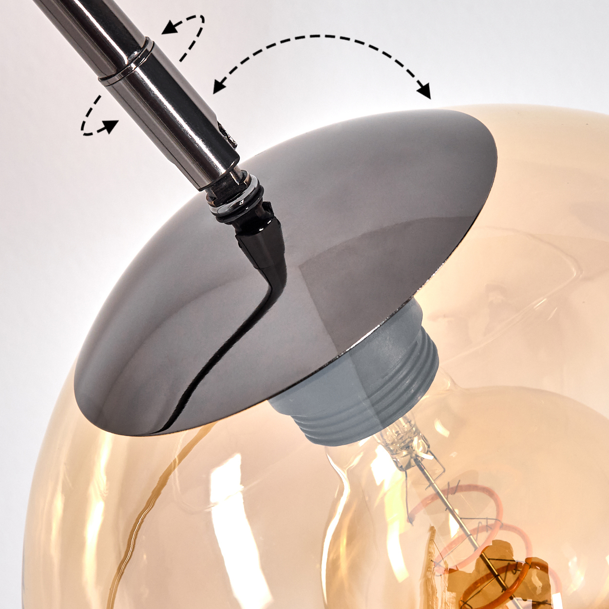 Nahaufnahme einer Lampe. Verfügt über einen Chromarm, einen dunklen Schirm und eine Glühbirne mit warmem Schein. Der Hintergrund ist weiß.