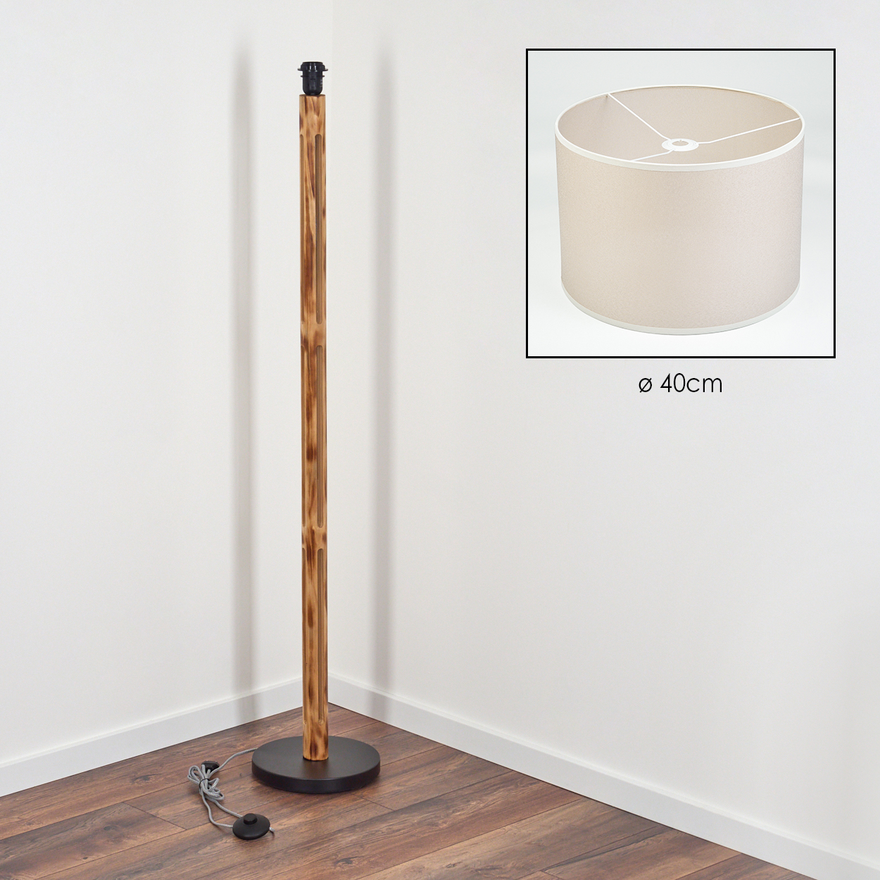 Eine Stehlampe aus Holz mit beigem Lampenschirm. Die Lampe steht in einer Ecke. Der Lampenschirm hat einen Durchmesser von 40 cm.