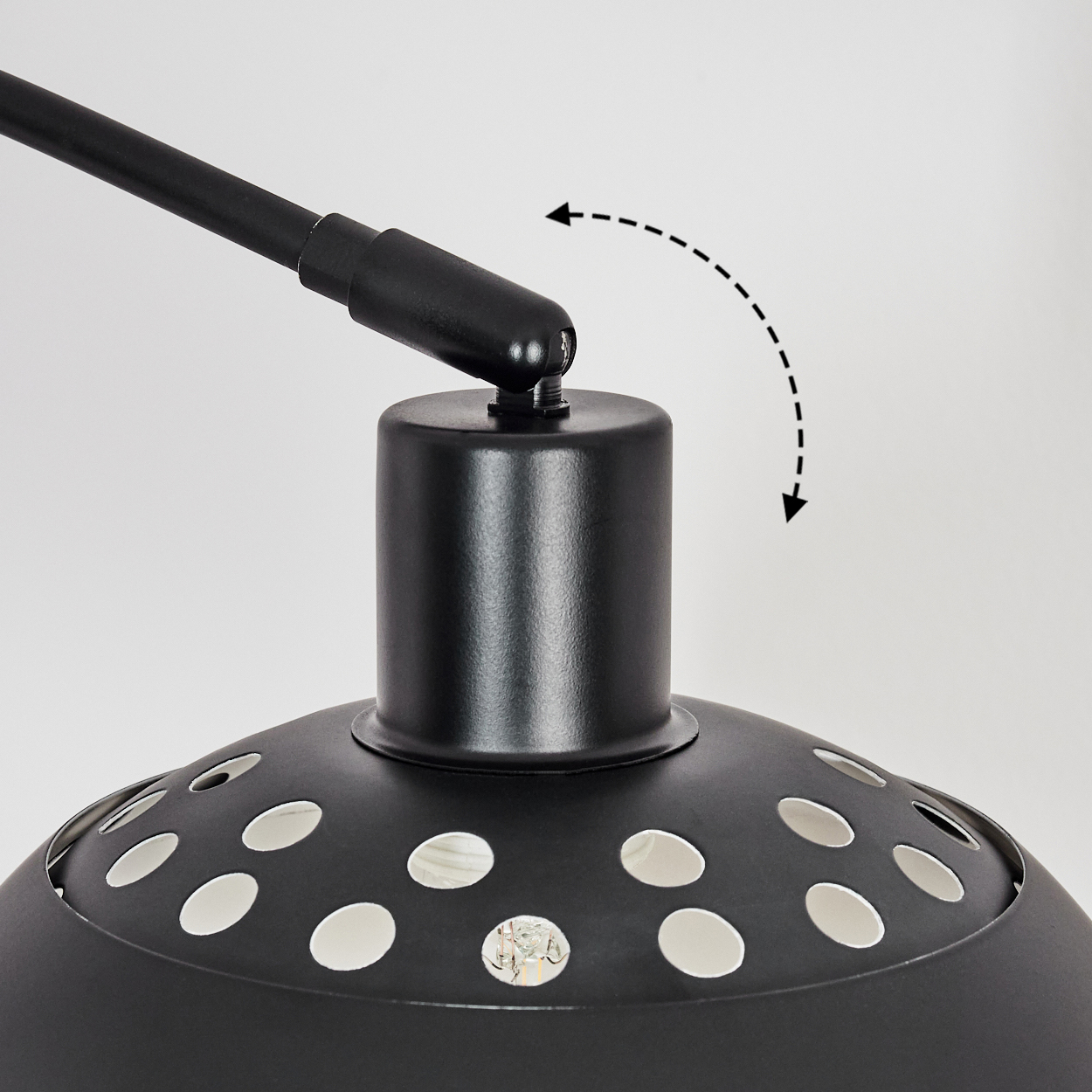 Nahaufnahme einer schwarzen Lampe mit perforiertem Lampenschirm. Der Lampenarm ist verstellbar. Gestrichelter Pfeil zeigt die Bewegung an.