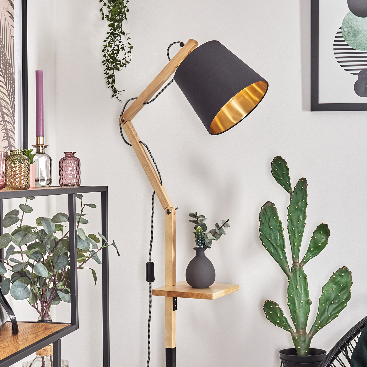 Ein modernes Zimmer mit einer Holzlampe, Pflanzen und einem schwarzen Rahmen. Ein Kaktus und ein Regal mit einer Vase sind ebenfalls vorhanden.